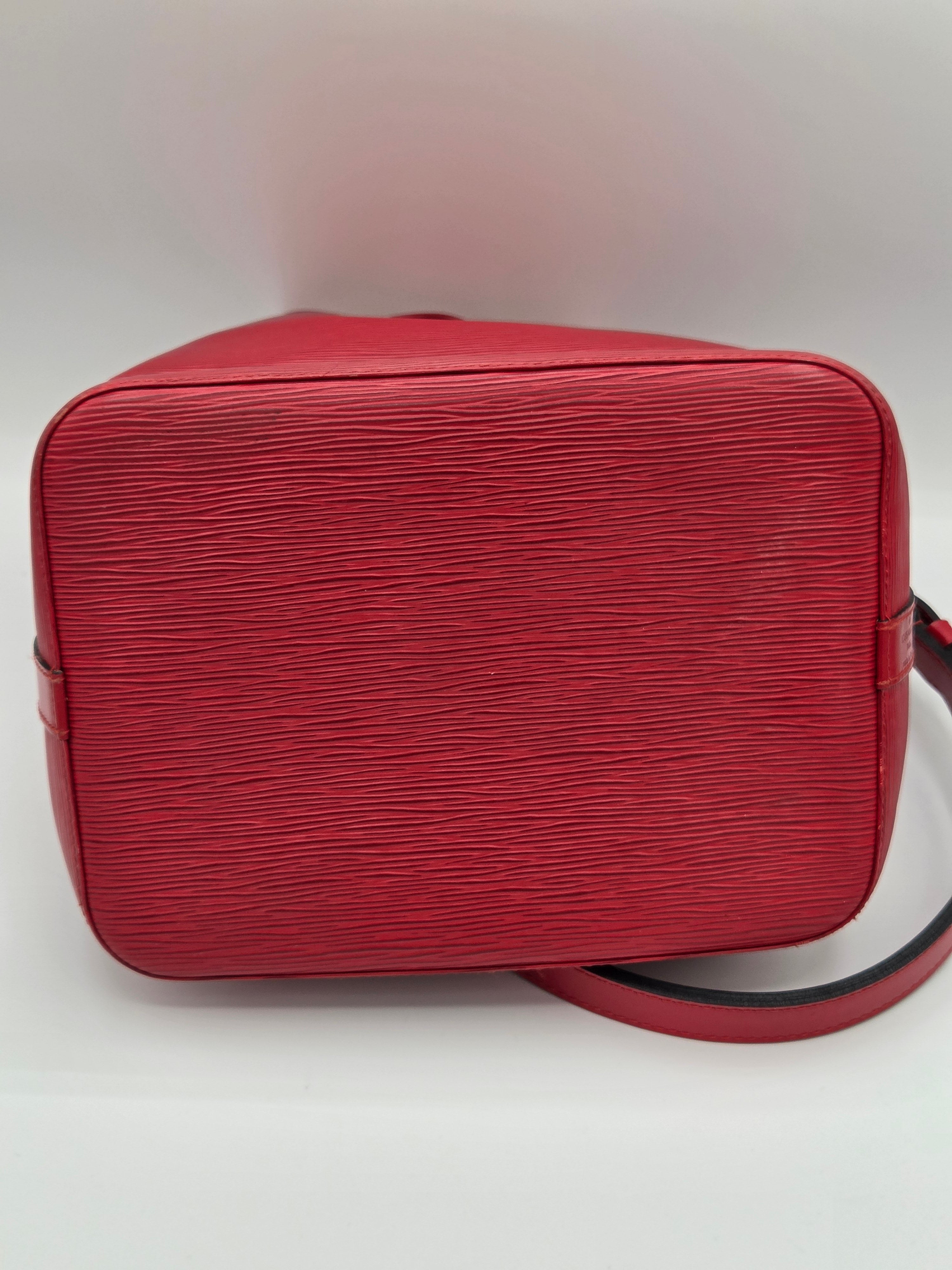 A red textured leather shoulder bag with a curved top handle, photographed from a top-down angle against a plain white background.