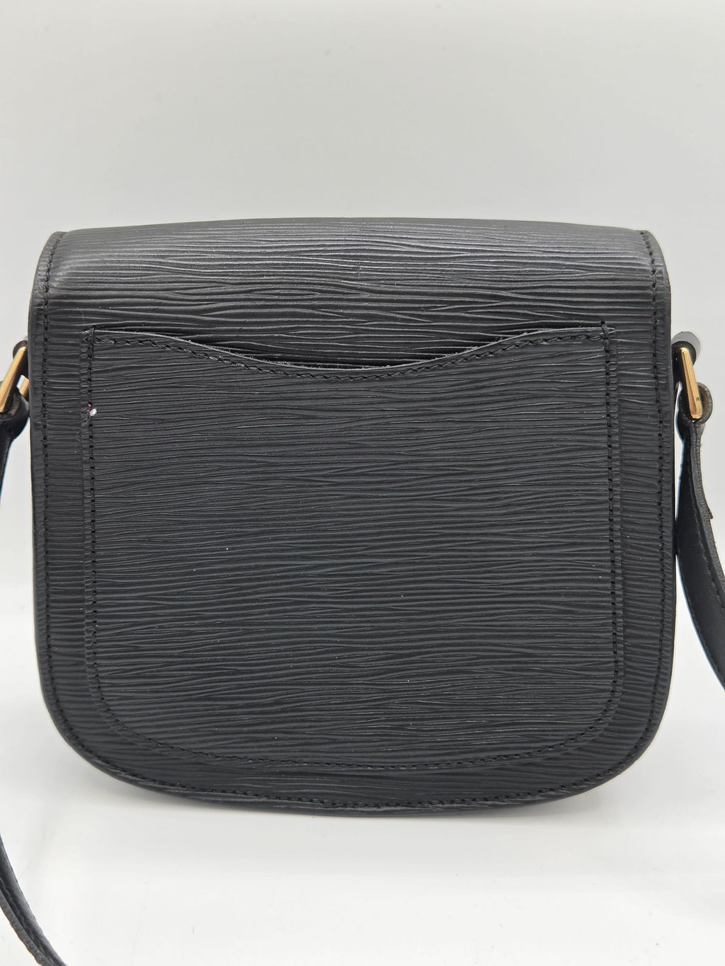A black textured leather crossbody bag with a front pocket, shown against a light gray background.