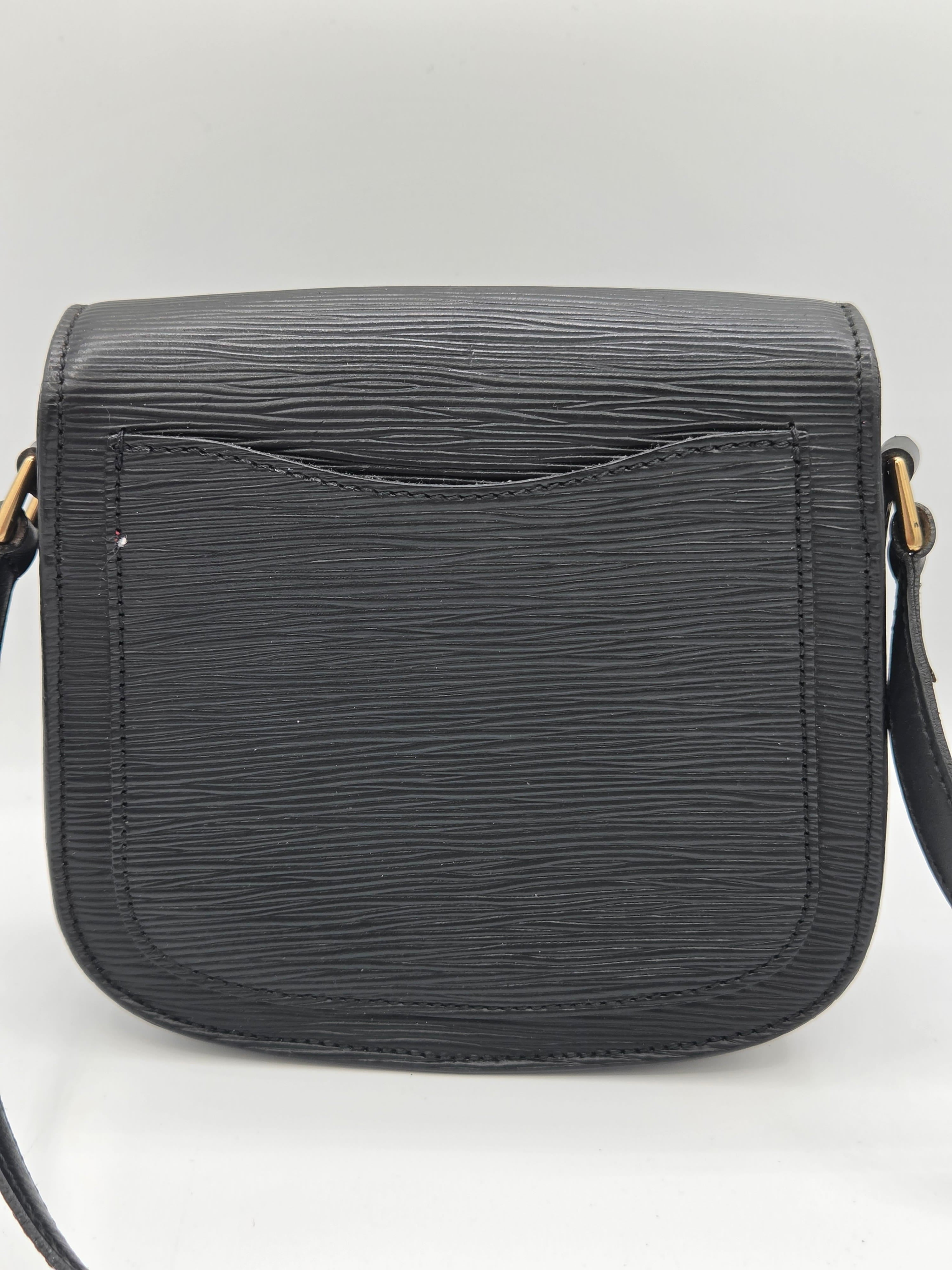 A black textured leather crossbody bag with a front pocket, shown against a light gray background.