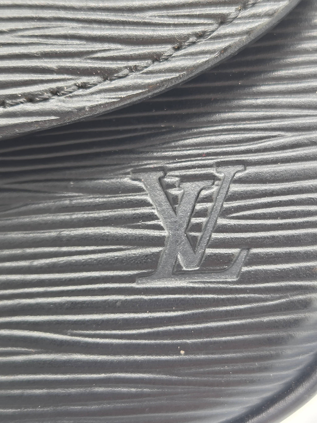 Close-up of a black textured leather item featuring an embossed Louis Vuitton LV logo.