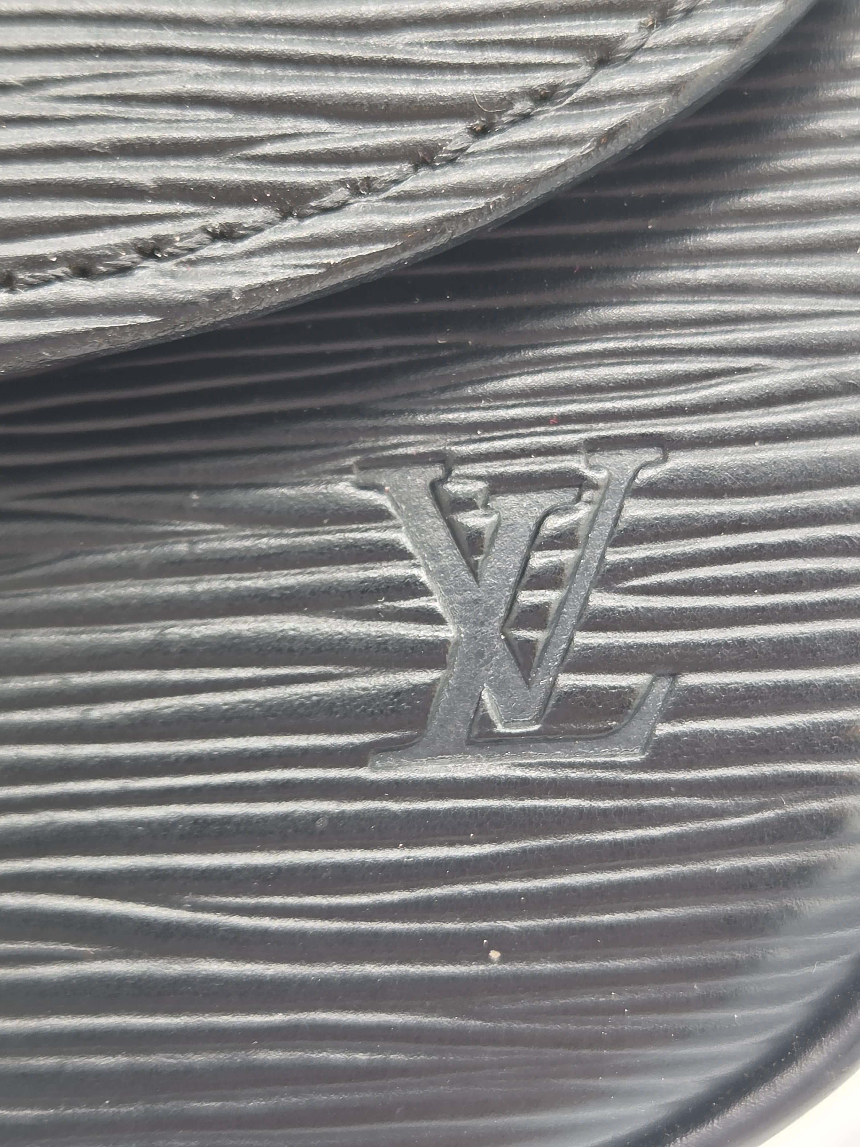 Close-up of a black textured leather item featuring an embossed Louis Vuitton LV logo.