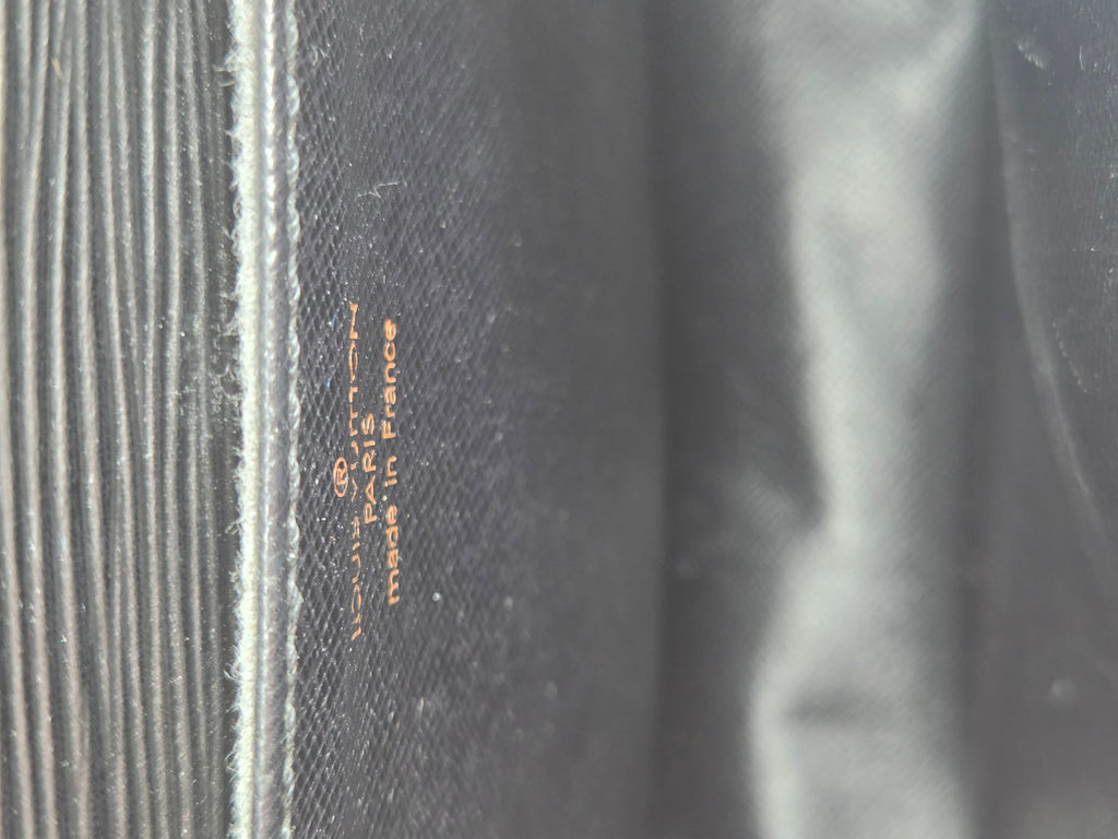 Close-up of a dark gray textured fabric with vertical ribbed stitching on the left and small orange text reading 'MADE IN FRANCE' and '100% COTTON'.