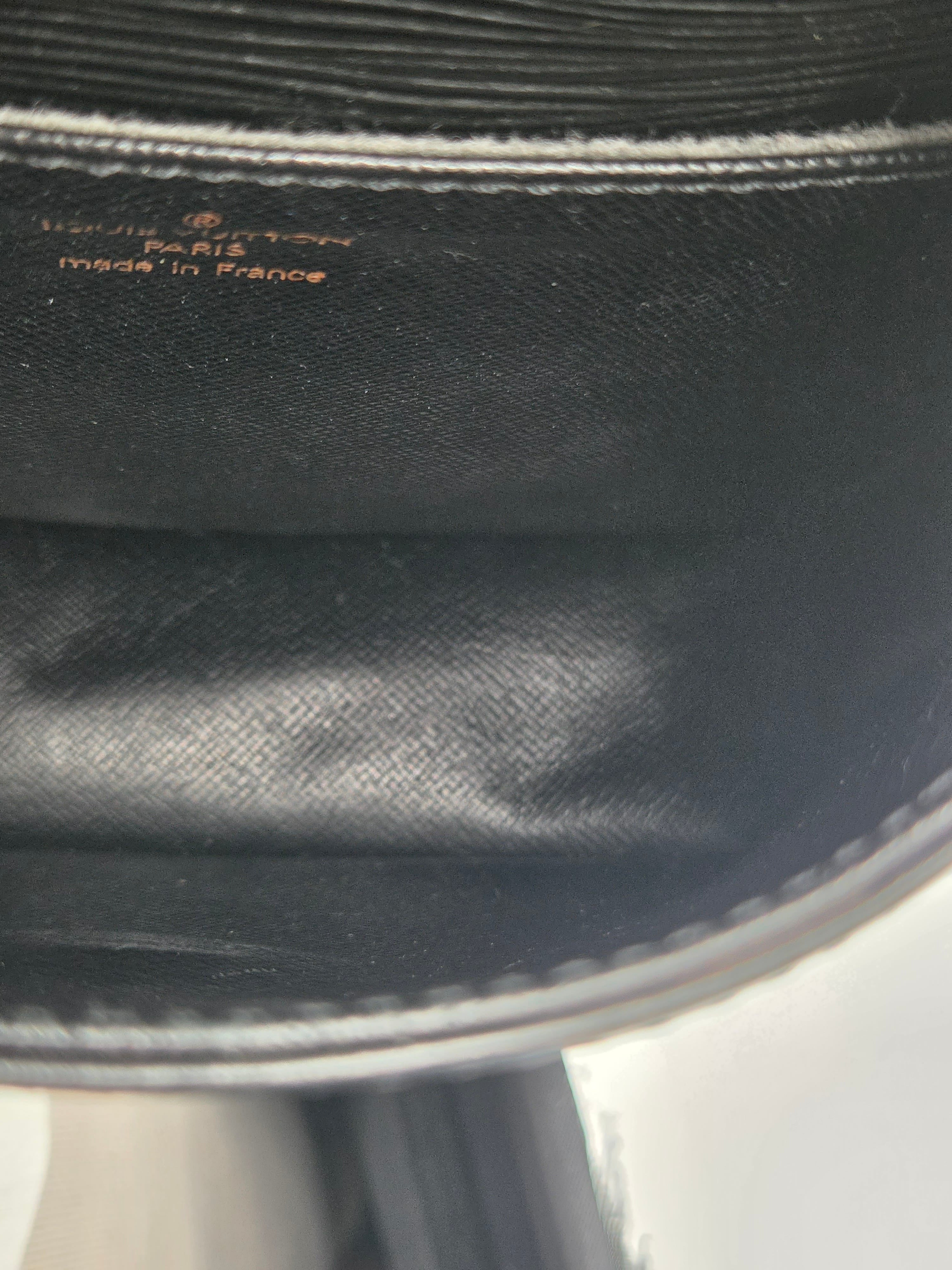 Close-up of the interior lining of a black handbag, showing the printed text 'Louis Vuitton Paris France made in France' on black textured fabric.