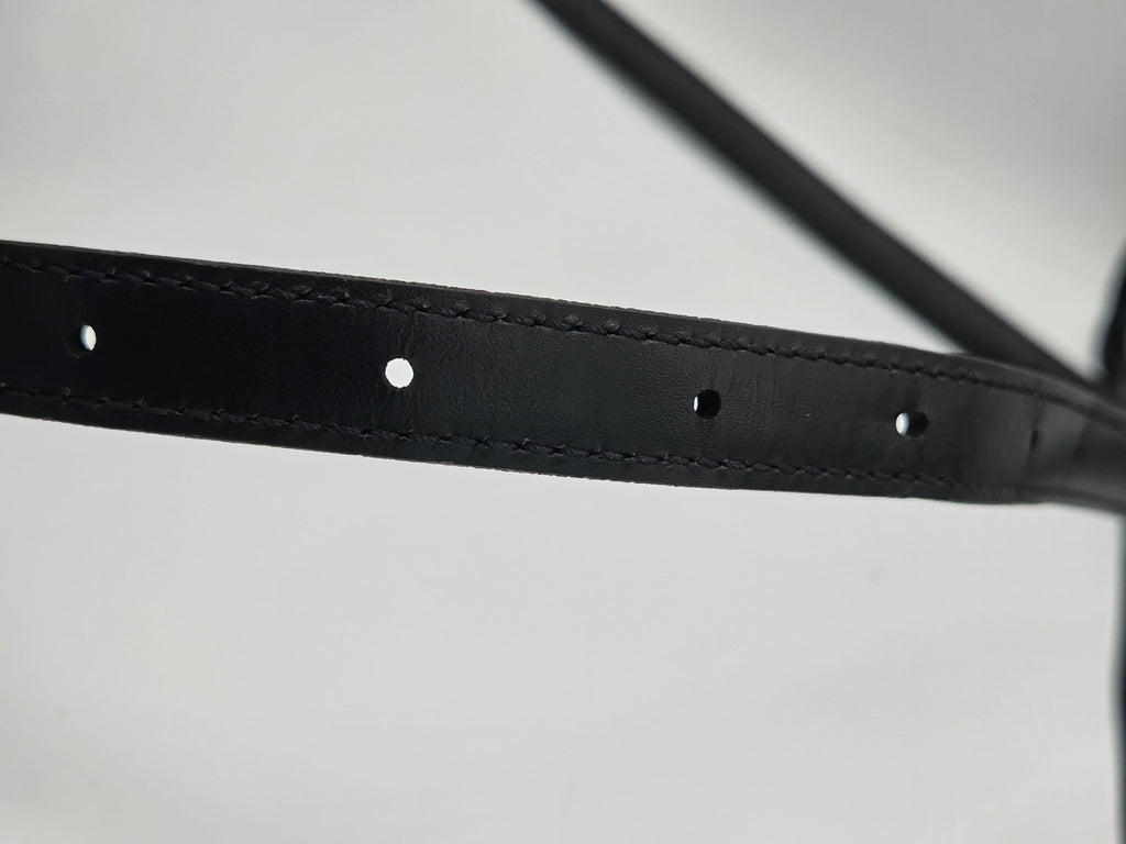 Close-up of a black leather strap with pre-drilled holes and fine stitching, shown against a light gray background.