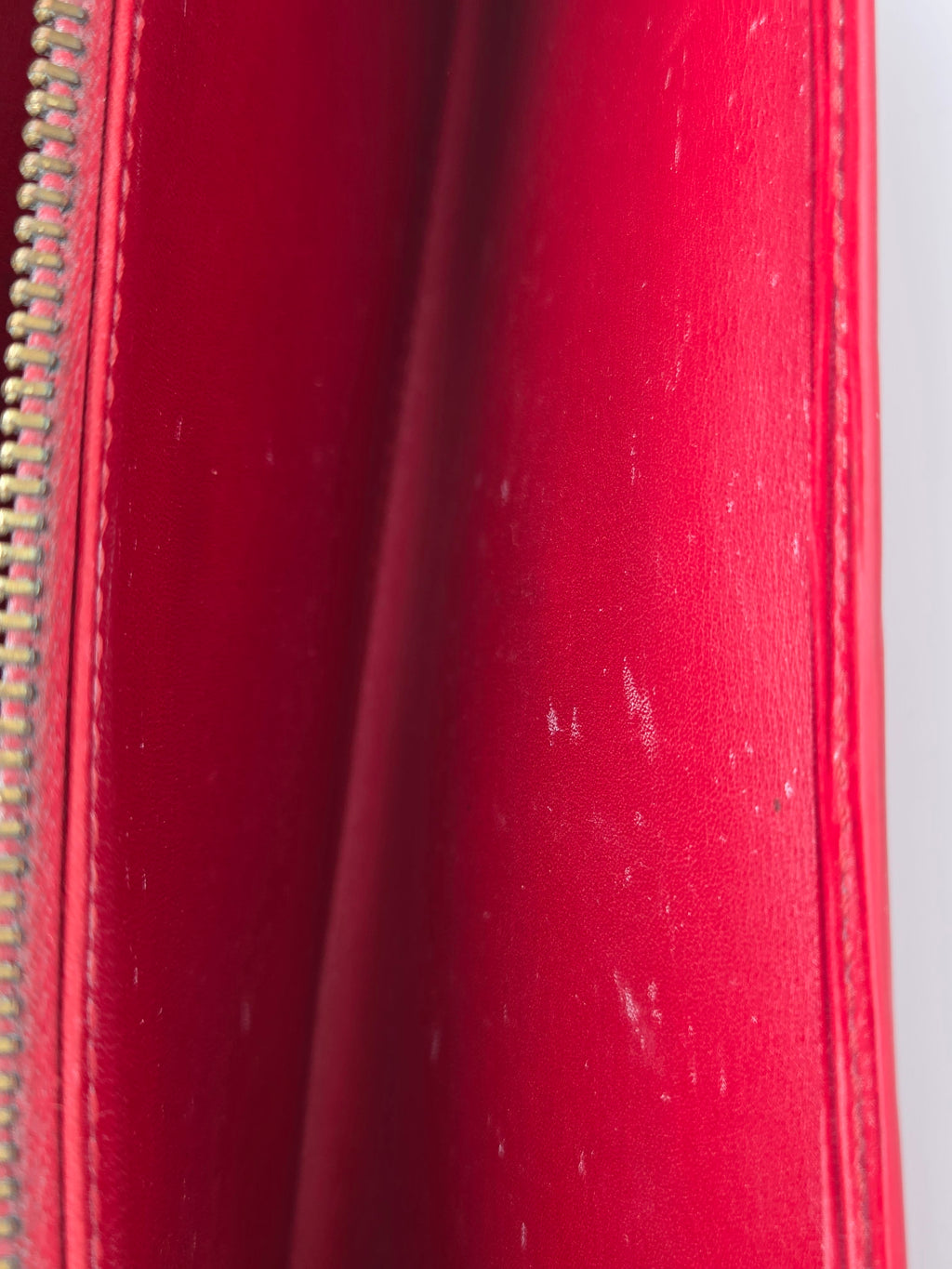 Close-up of a red leather zippered pouch or wallet showing the interior lining and a gold-tone zipper.