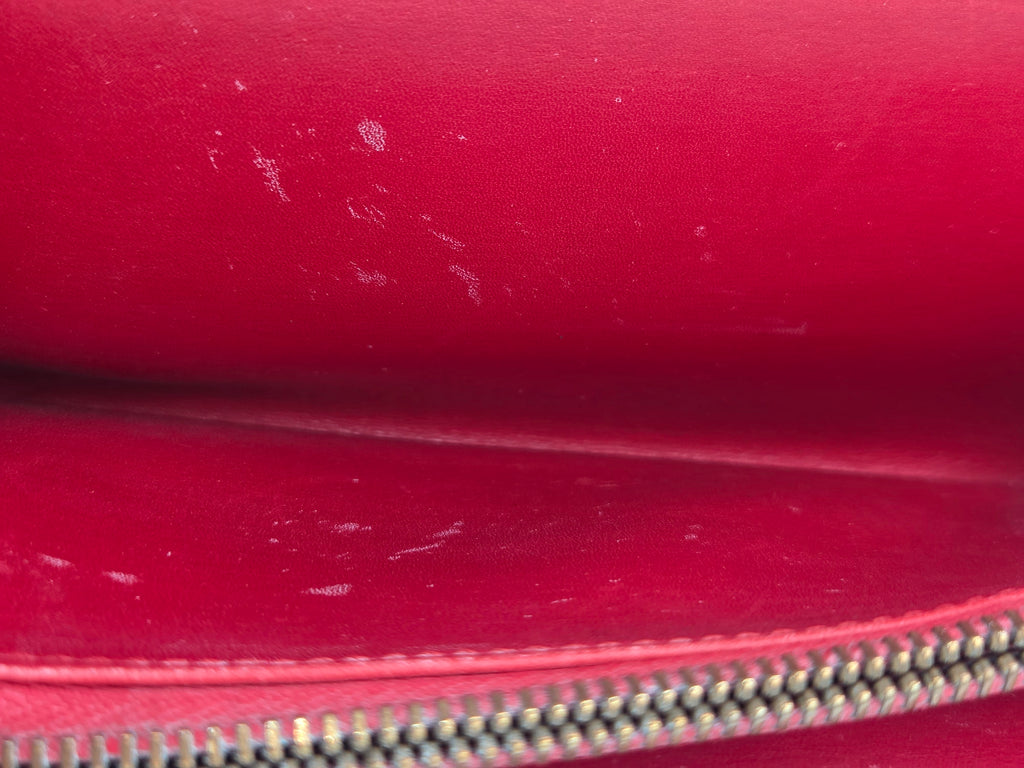 Close-up of a red leather zippered pouch interior showing some scuffs and wear on the surface.