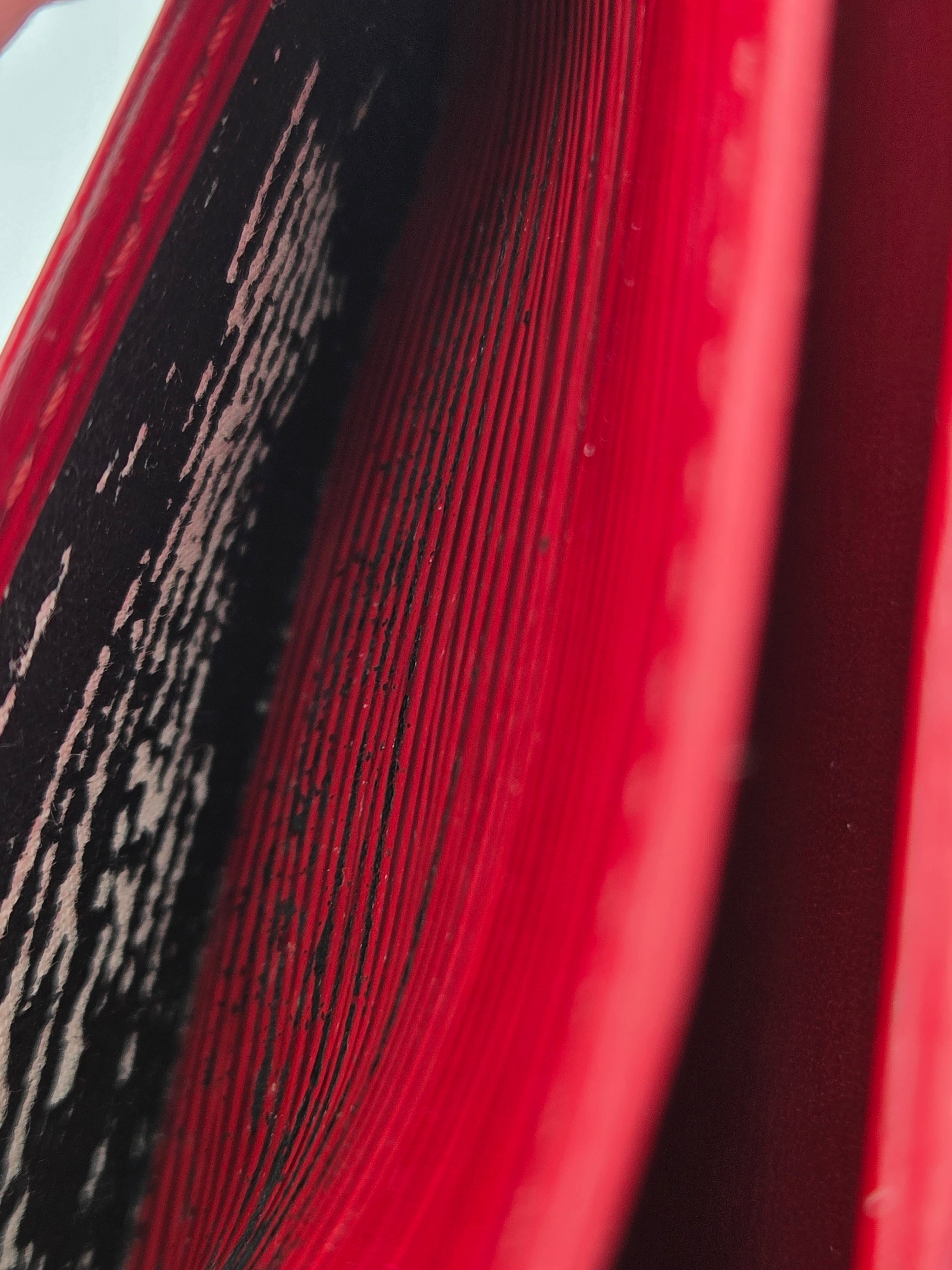 Close-up detail of a red book or notebook with tightly stacked pages and a black textured cover or underside.