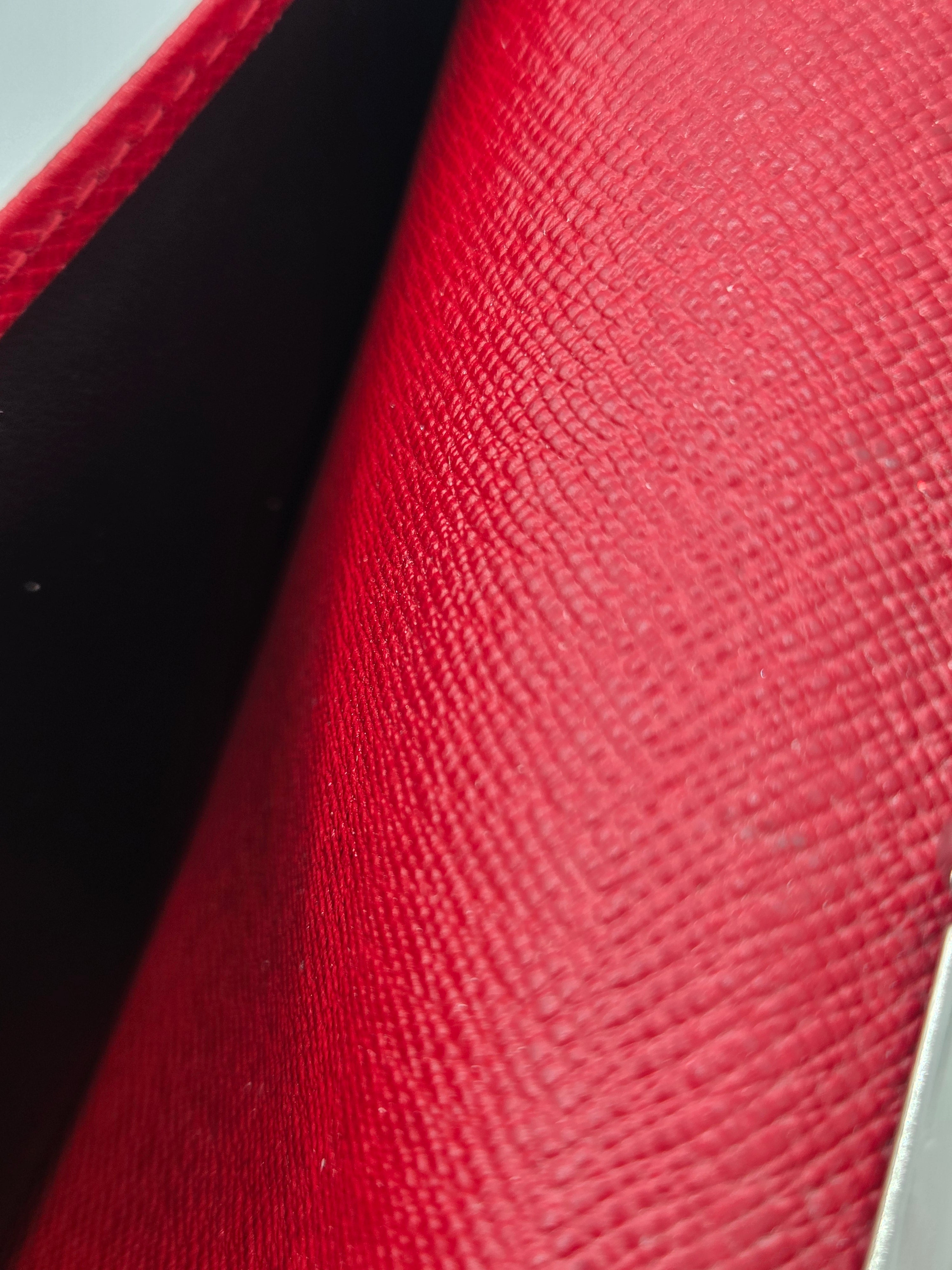 Close-up of a red textured leather surface with a black interior visible in the fold.