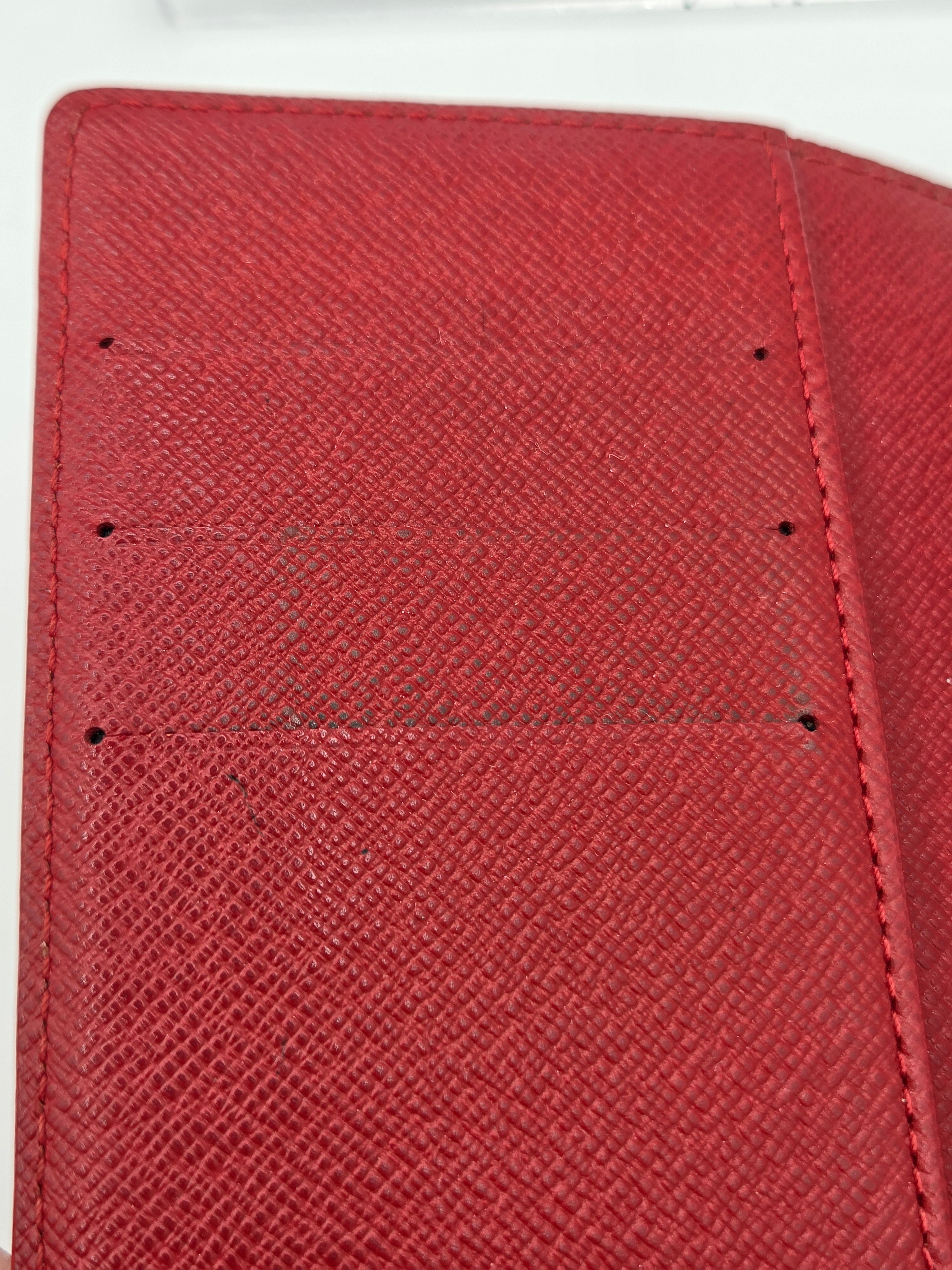 Close-up of a red textured leather wallet or card holder showing the interior lining with stitched compartments and small holes.