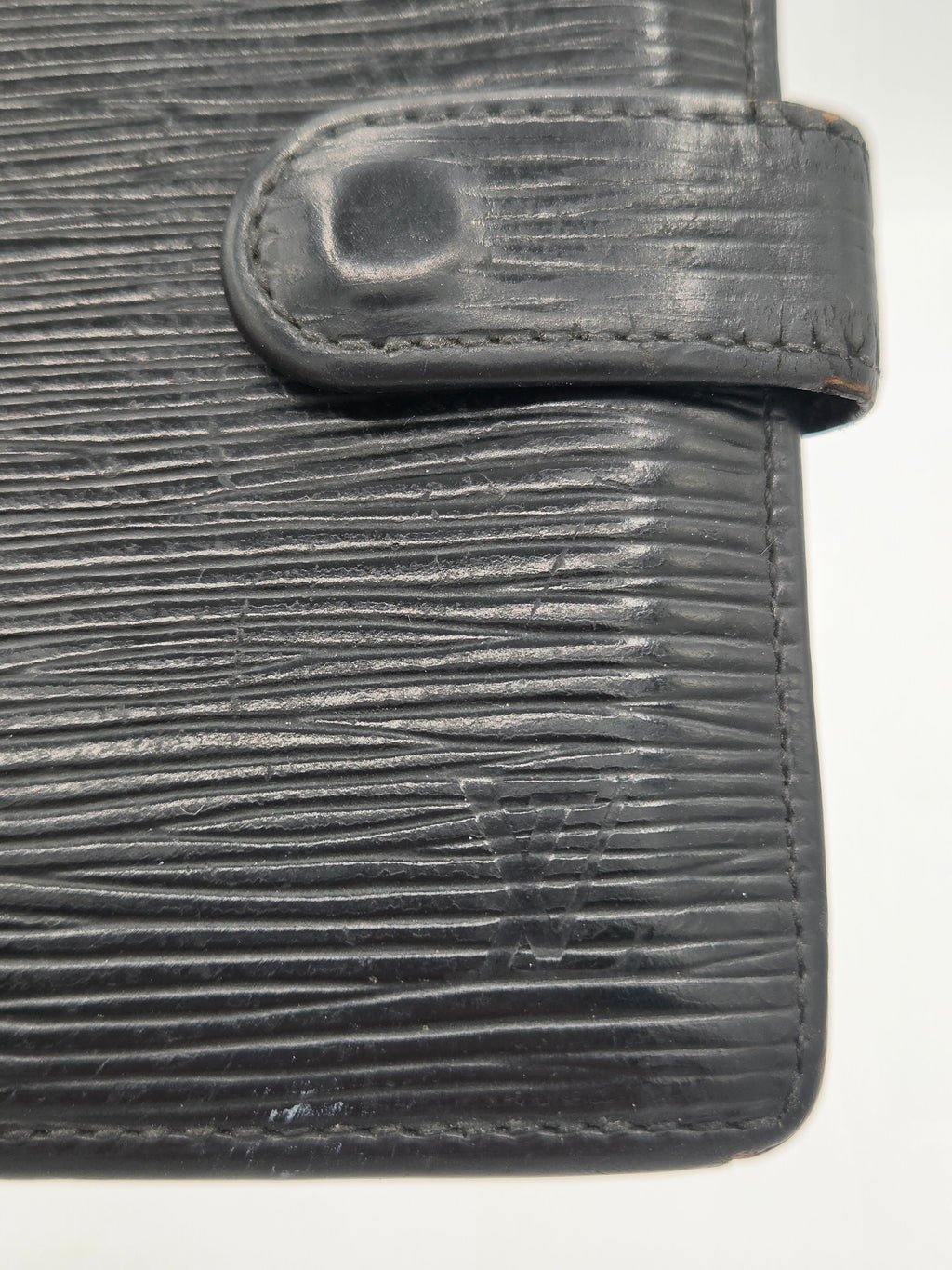 Close-up of a dark gray textured leather wallet showing the vertical grain pattern and snap tab closure against a plain white background.