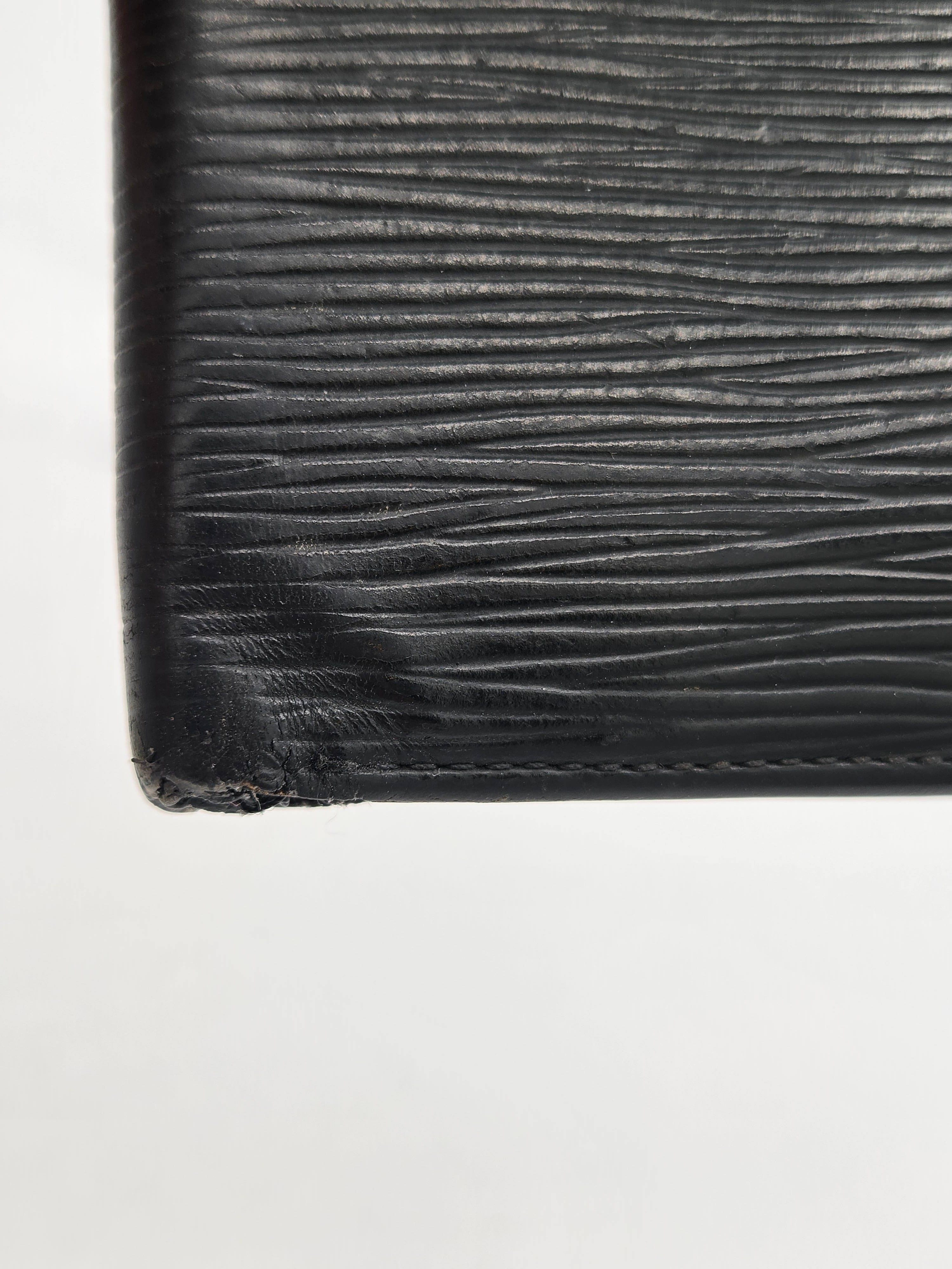 Close-up of a black textured leather item corner with visible wear and frayed edge on a plain white background.