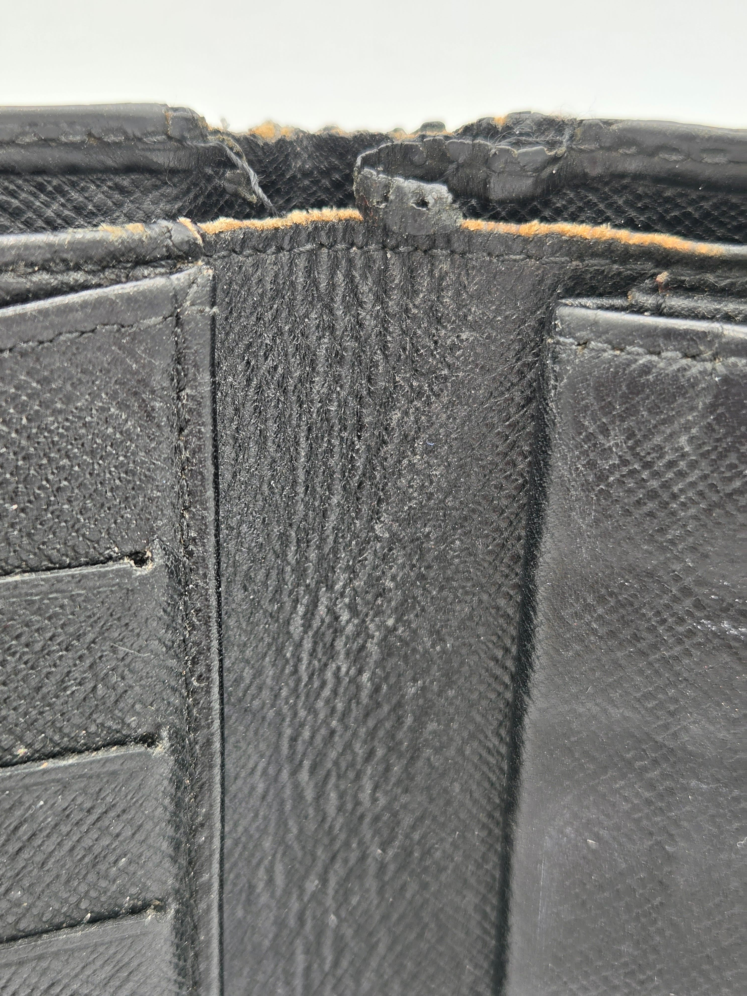Close-up of a black textured leather wallet showing the interior lining, stitching, and a worn, frayed edge.