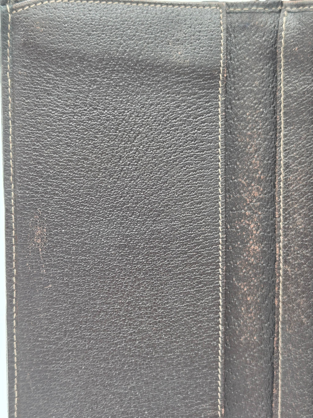 Close-up of a dark gray textured leather wallet showing the grain pattern and stitching details.