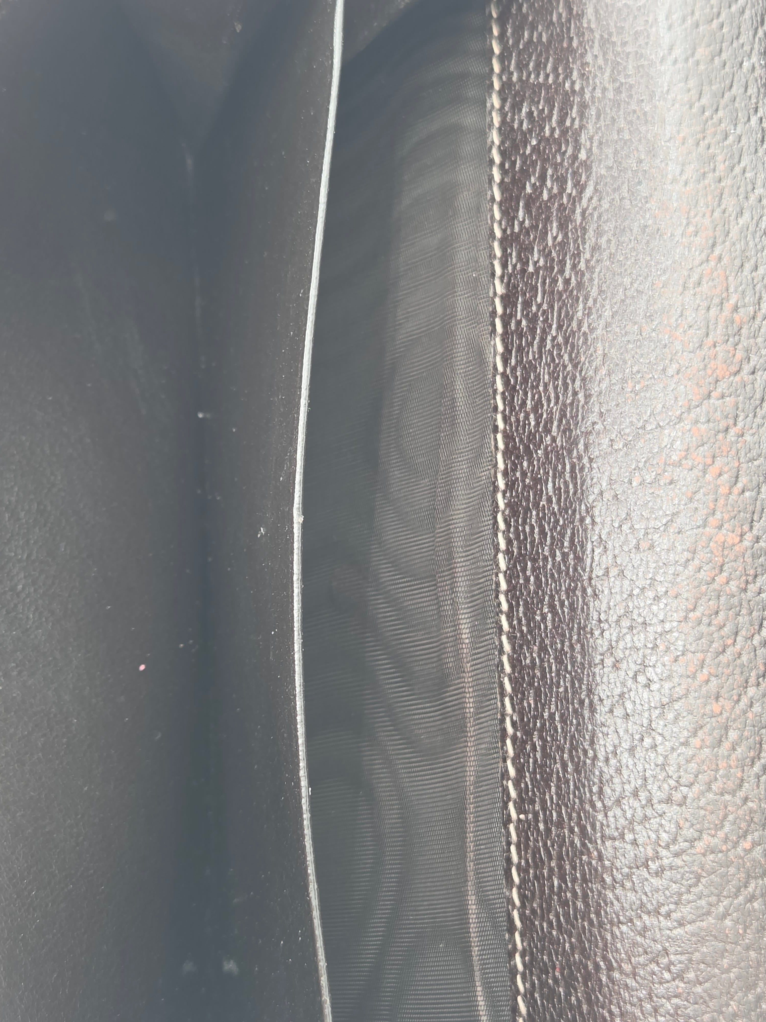 Close-up of a dark brown textured leather interior with white contrast stitching and a dark fabric lining.