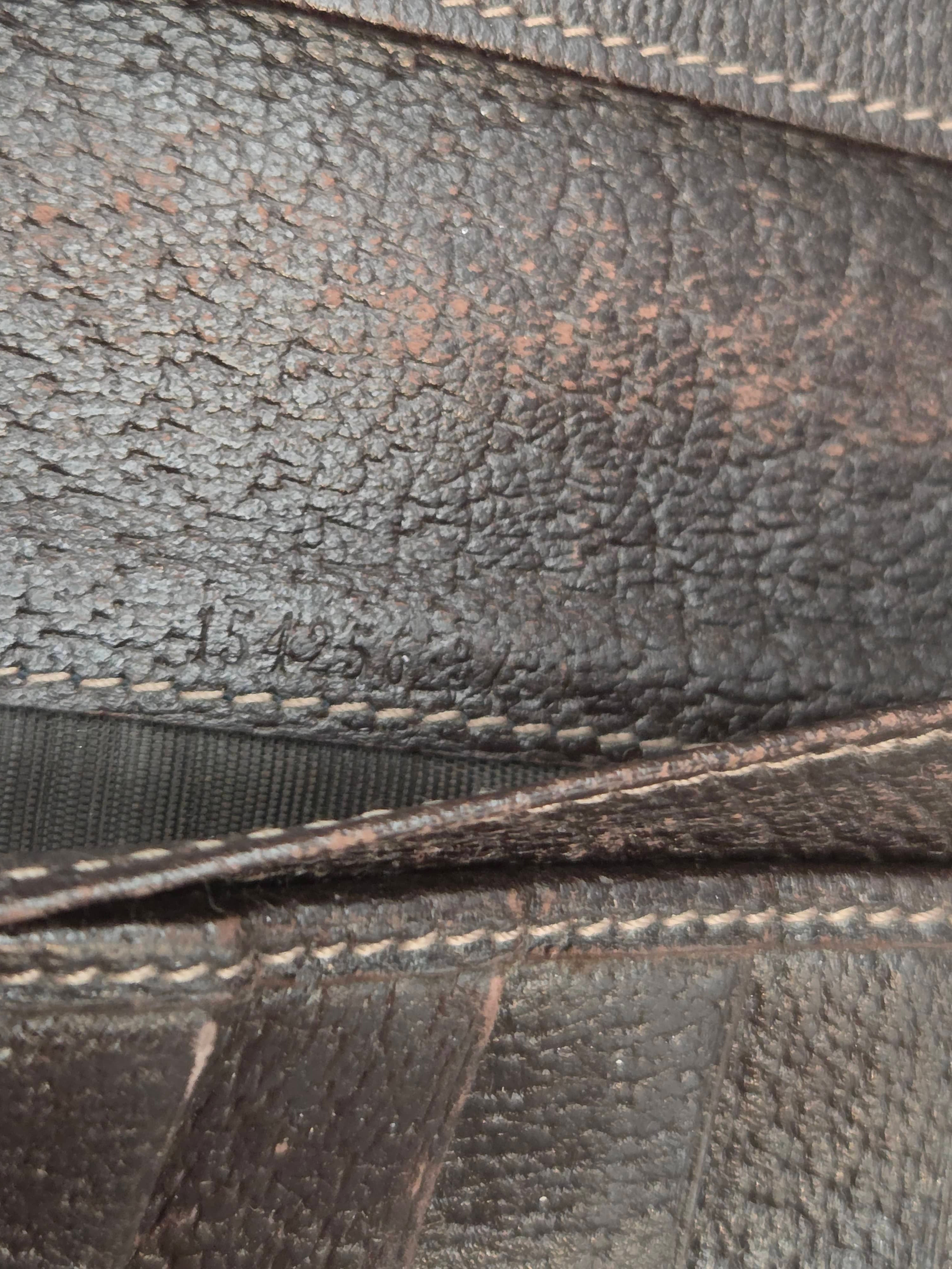 Close-up of dark brown textured leather with visible grain and contrast stitching along the edges.