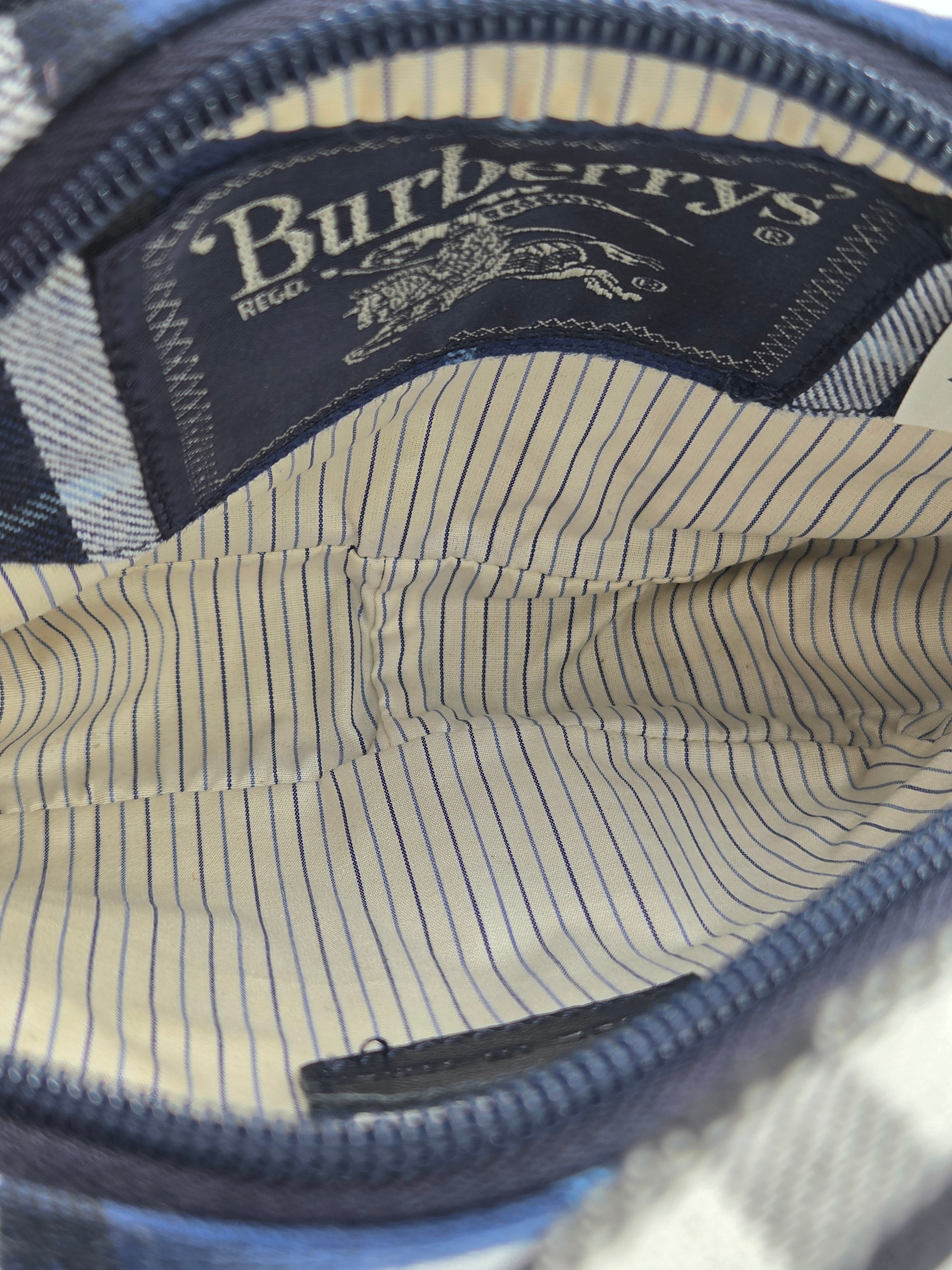 Close-up of the interior of a Burberry bag, showing a navy blue zipper, a cream and navy striped lining, and a visible Burberry brand label.