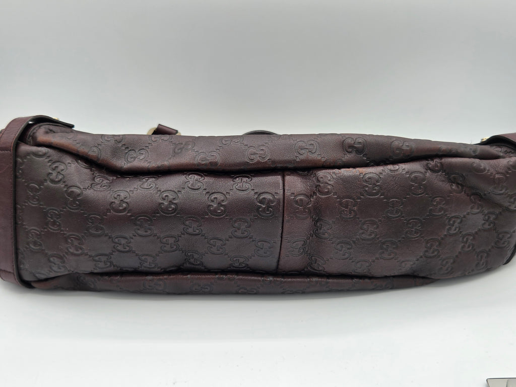 A dark brown Gucci shoulder bag featuring the brand's signature embossed GG monogram pattern, shown against a plain light gray background.