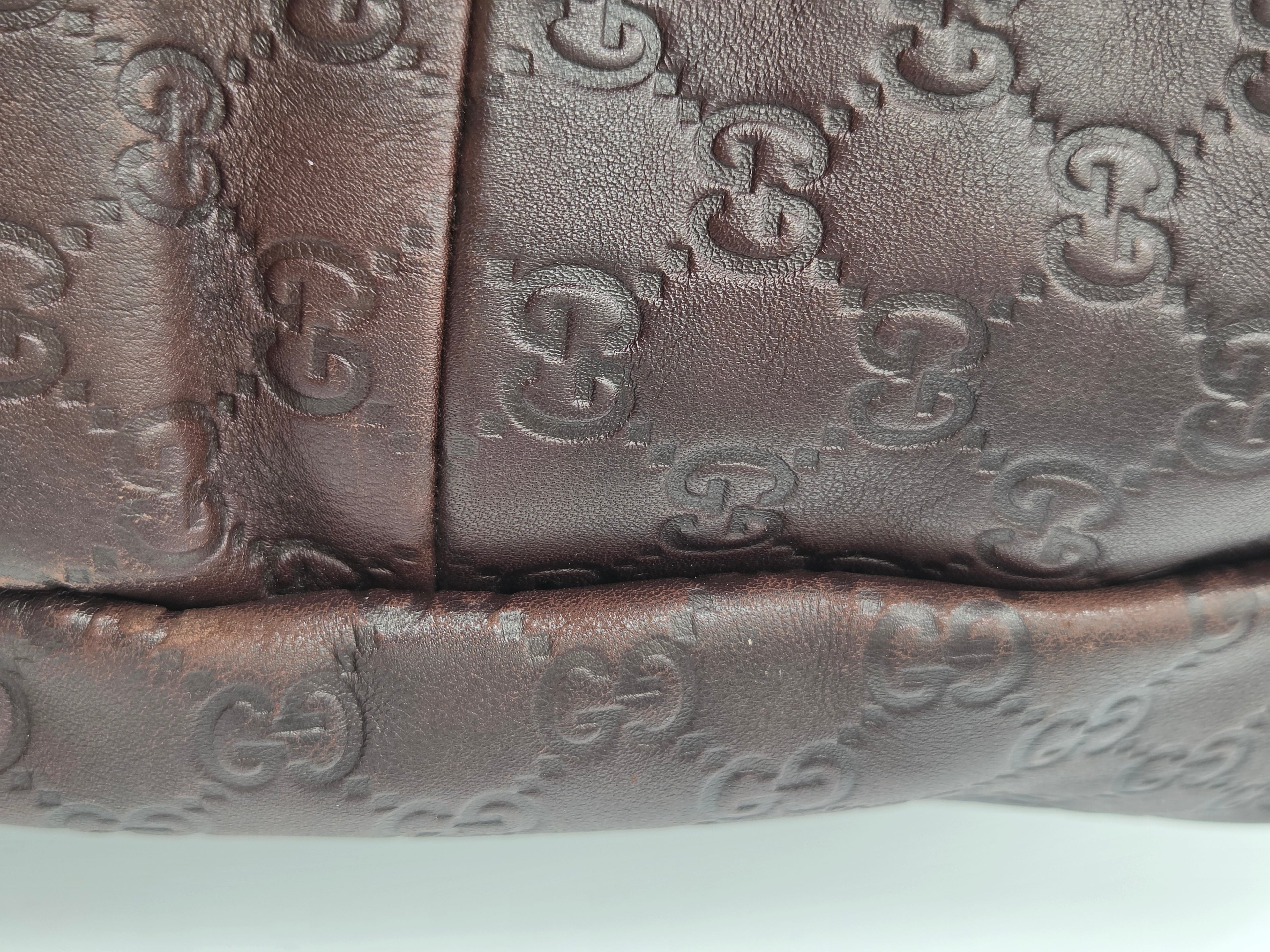 Close-up of a dark brown leather item featuring the embossed Gucci GG monogram pattern.