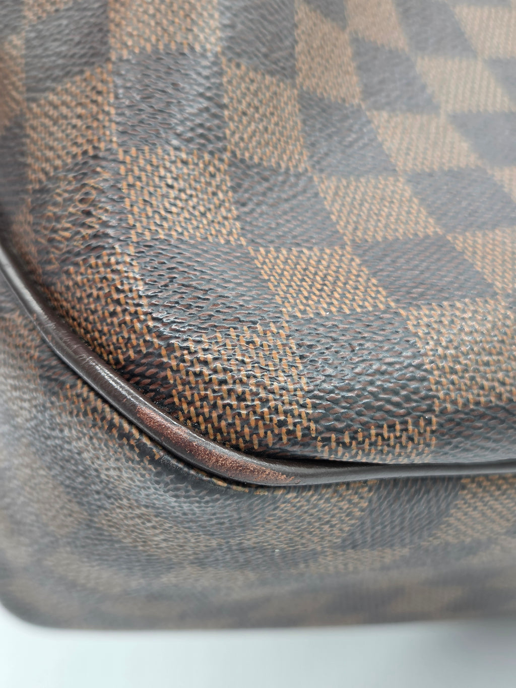 Close-up of a Louis Vuitton handbag in the Damier Azur canvas, showing the signature brown and gray checkered pattern and a dark brown leather trim.