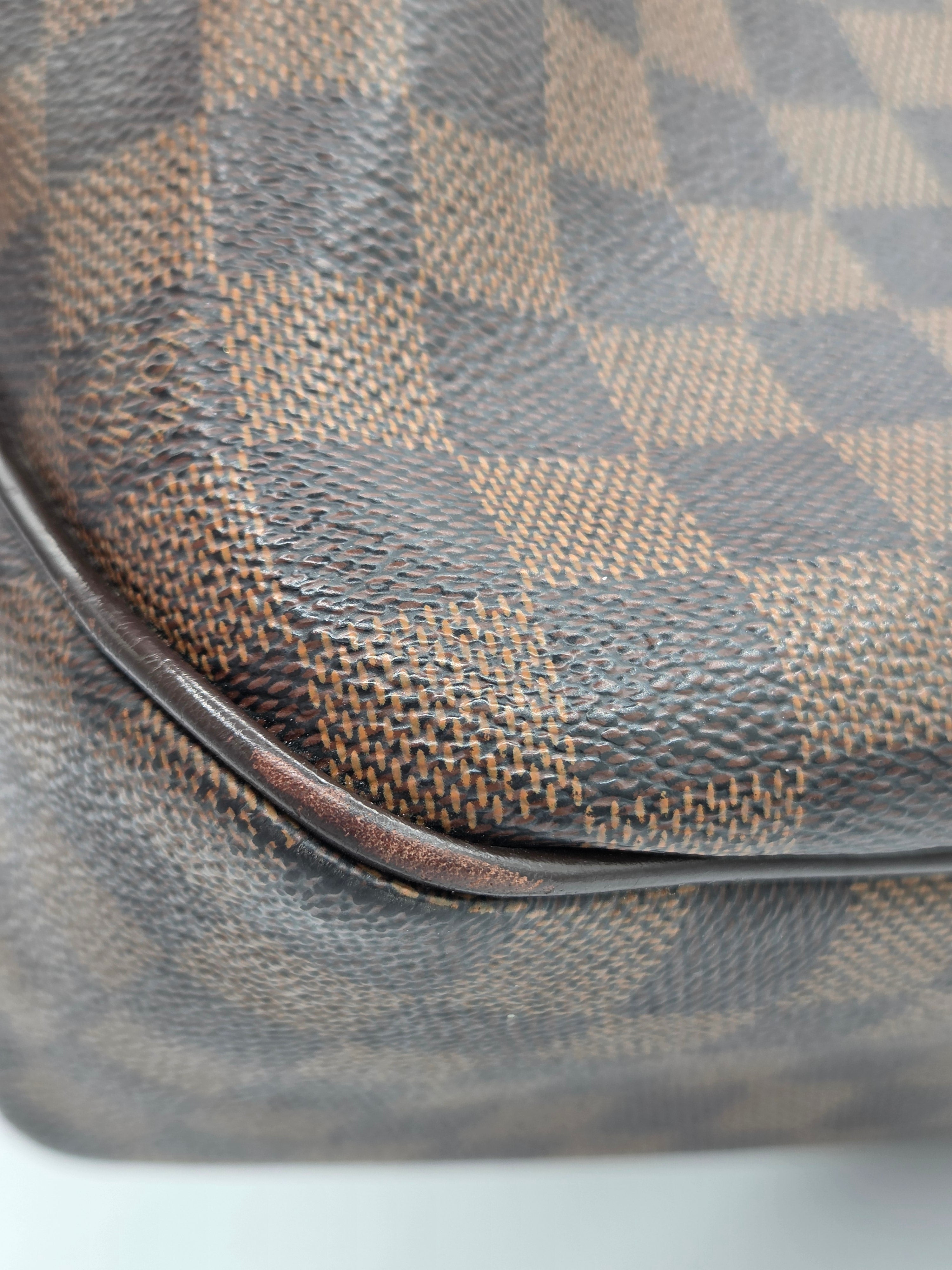 Close-up of a Louis Vuitton handbag in the Damier Azur canvas, showing the signature brown and gray checkered pattern and a dark brown leather trim.