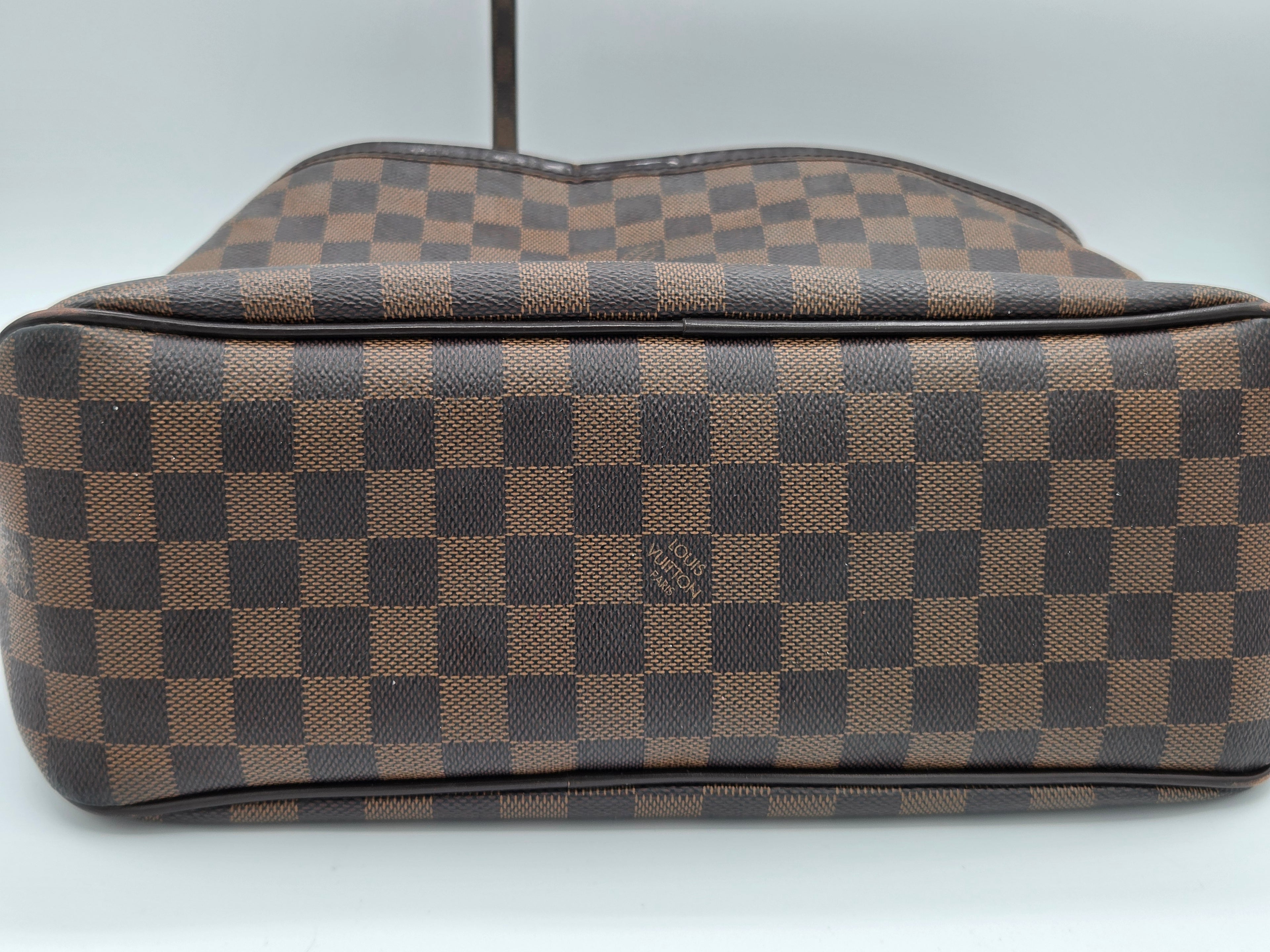 A Louis Vuitton shoulder bag in the Damier Ebene checkered canvas, featuring a brown and dark brown checkerboard pattern with a small embossed LV logo on the front.
