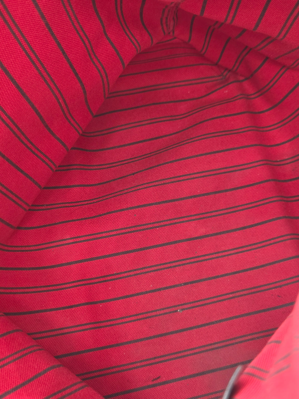 A close-up of a red fabric with thin black vertical pinstripes, showing the material texture and folds.