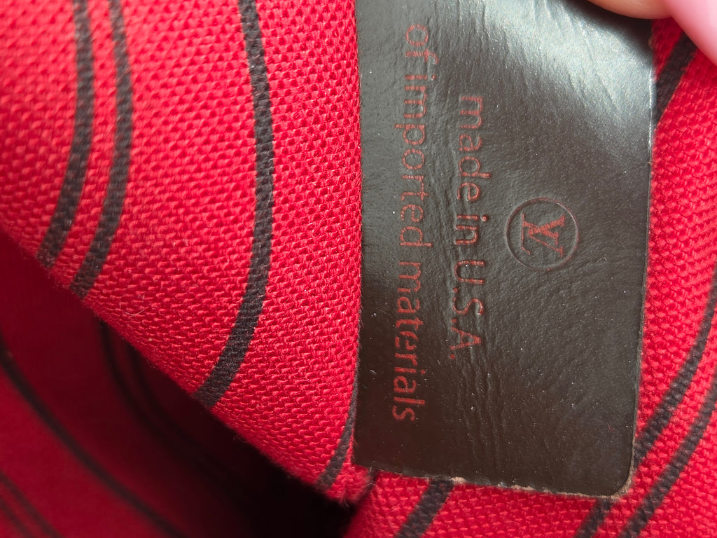 Close-up of a red woven textile with black diagonal stripes and a dark brown leather tag reading 'made in U.S.