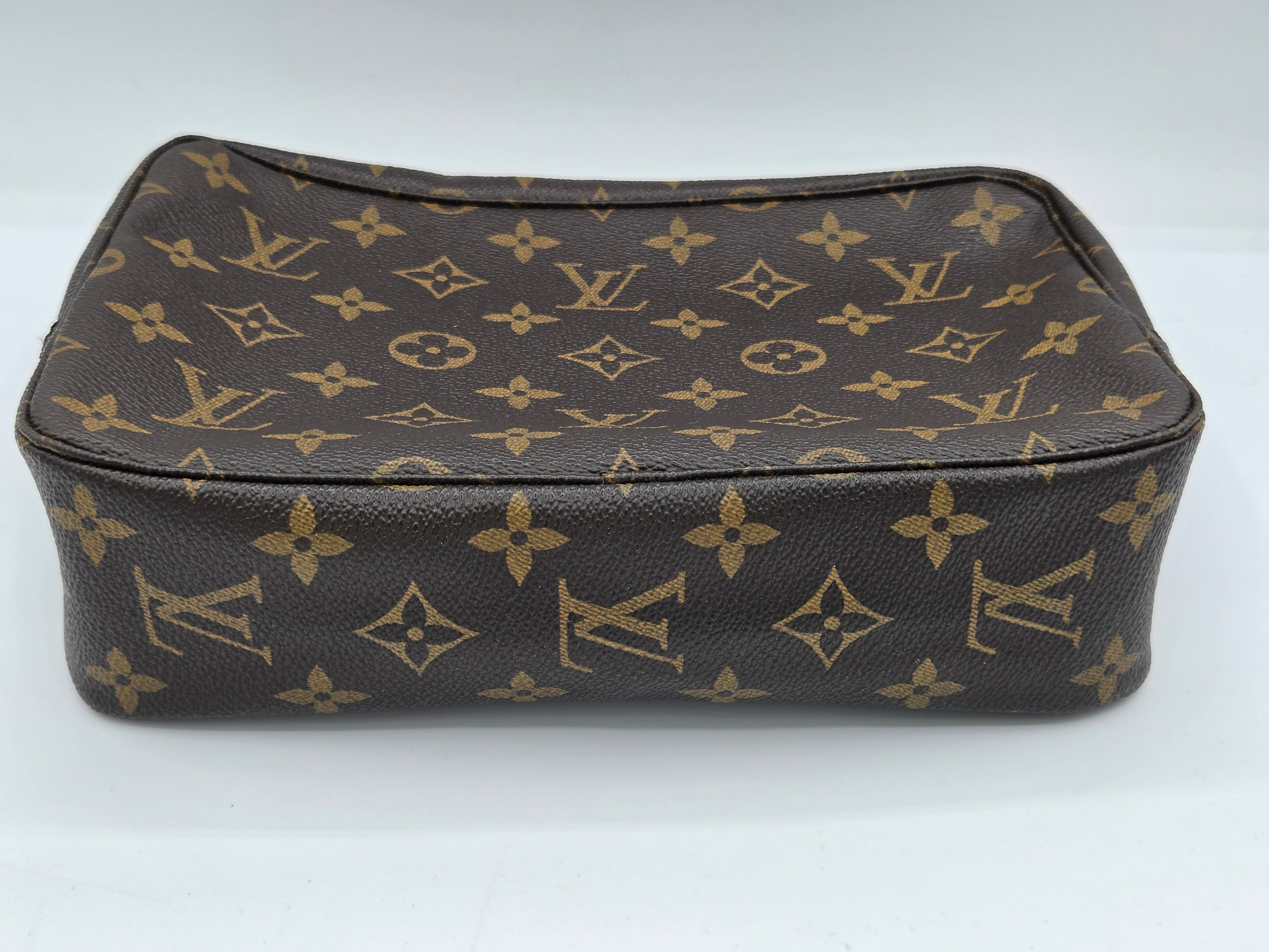 A Louis Vuitton monogram canvas pouch in dark brown and tan, photographed on a plain white background.