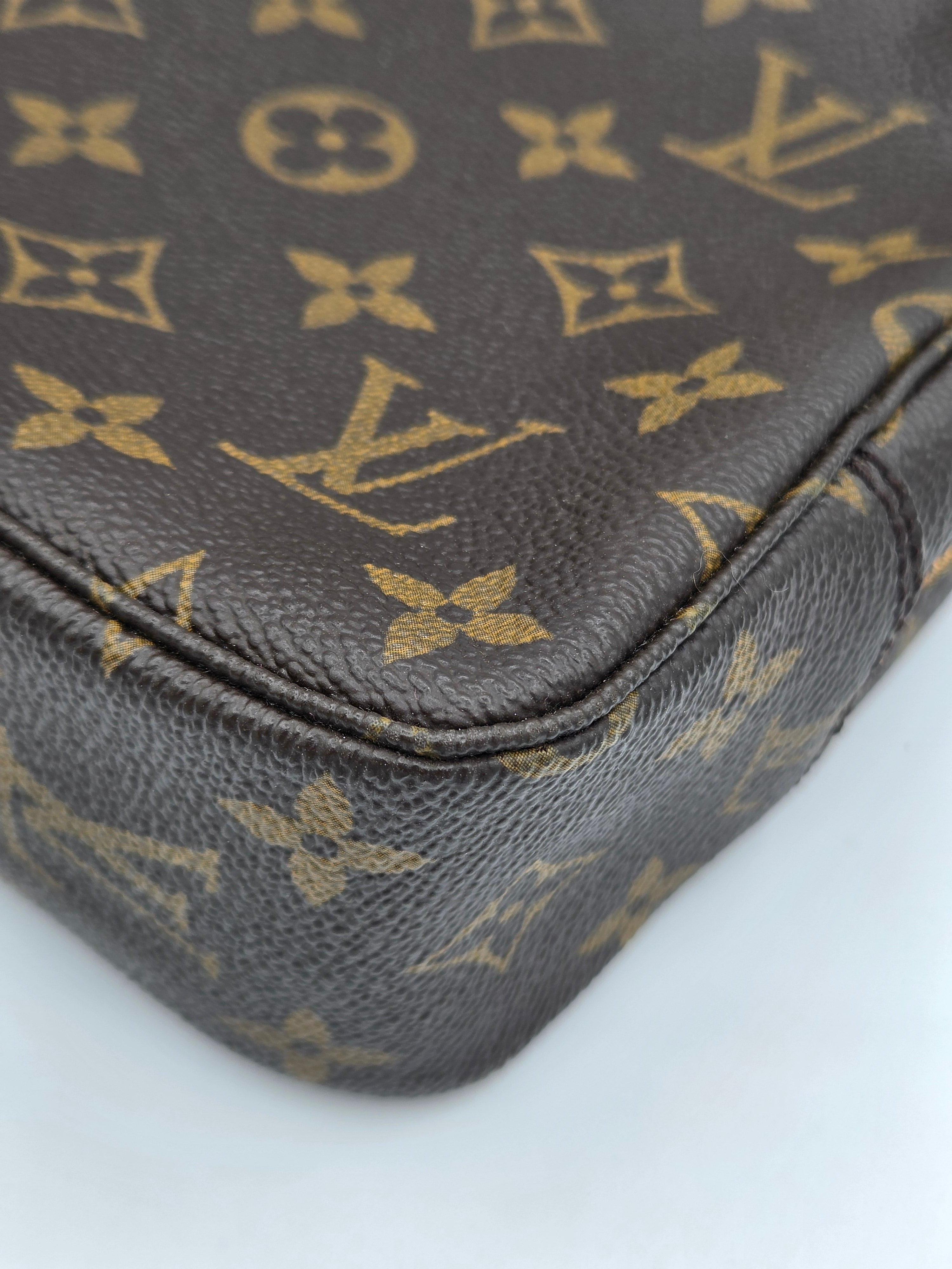 Close-up of a Louis Vuitton monogram canvas bag corner, showing the classic brown and gold LV pattern and pebbled leather texture on a white background.
