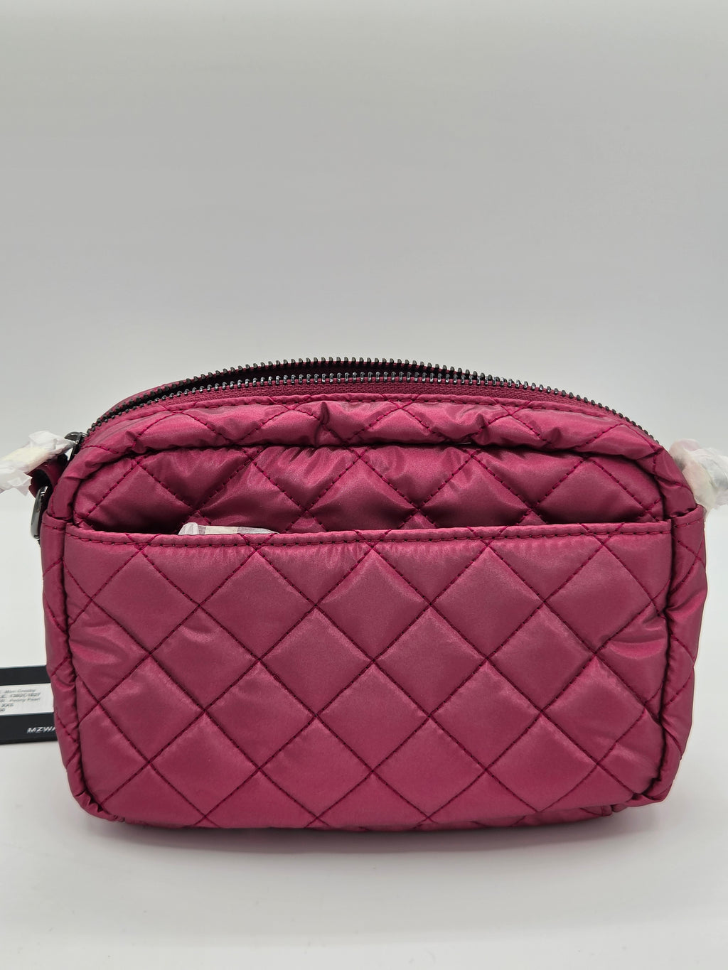 A quilted magenta pink nylon cosmetic pouch with a diagonal zipper, shown on a neutral gray background.