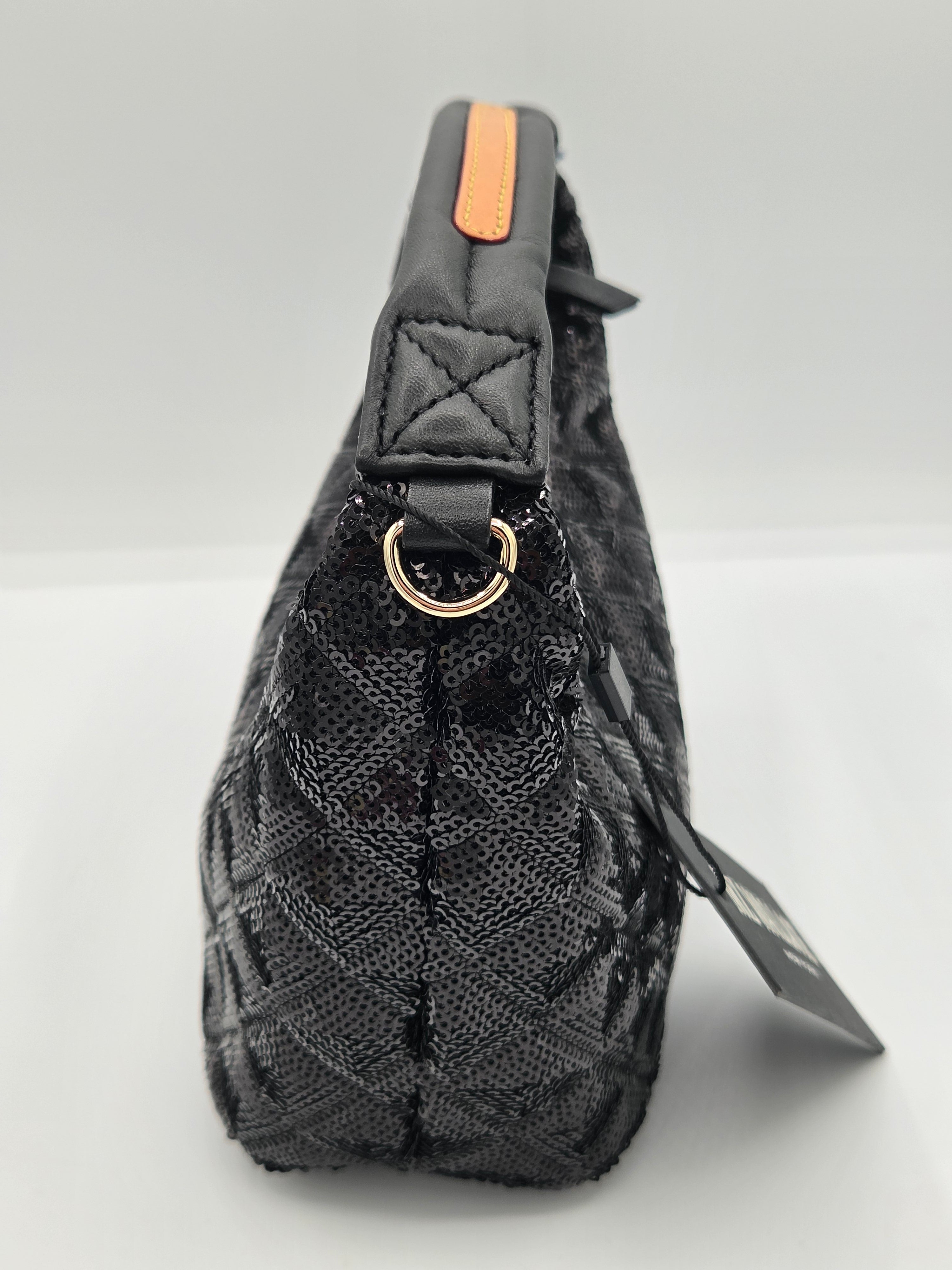 A black quilted leather shoulder bag with a gold-tone metal ring and a small orange accent tab on the handle, shown against a light gray background with a product tag attached.
