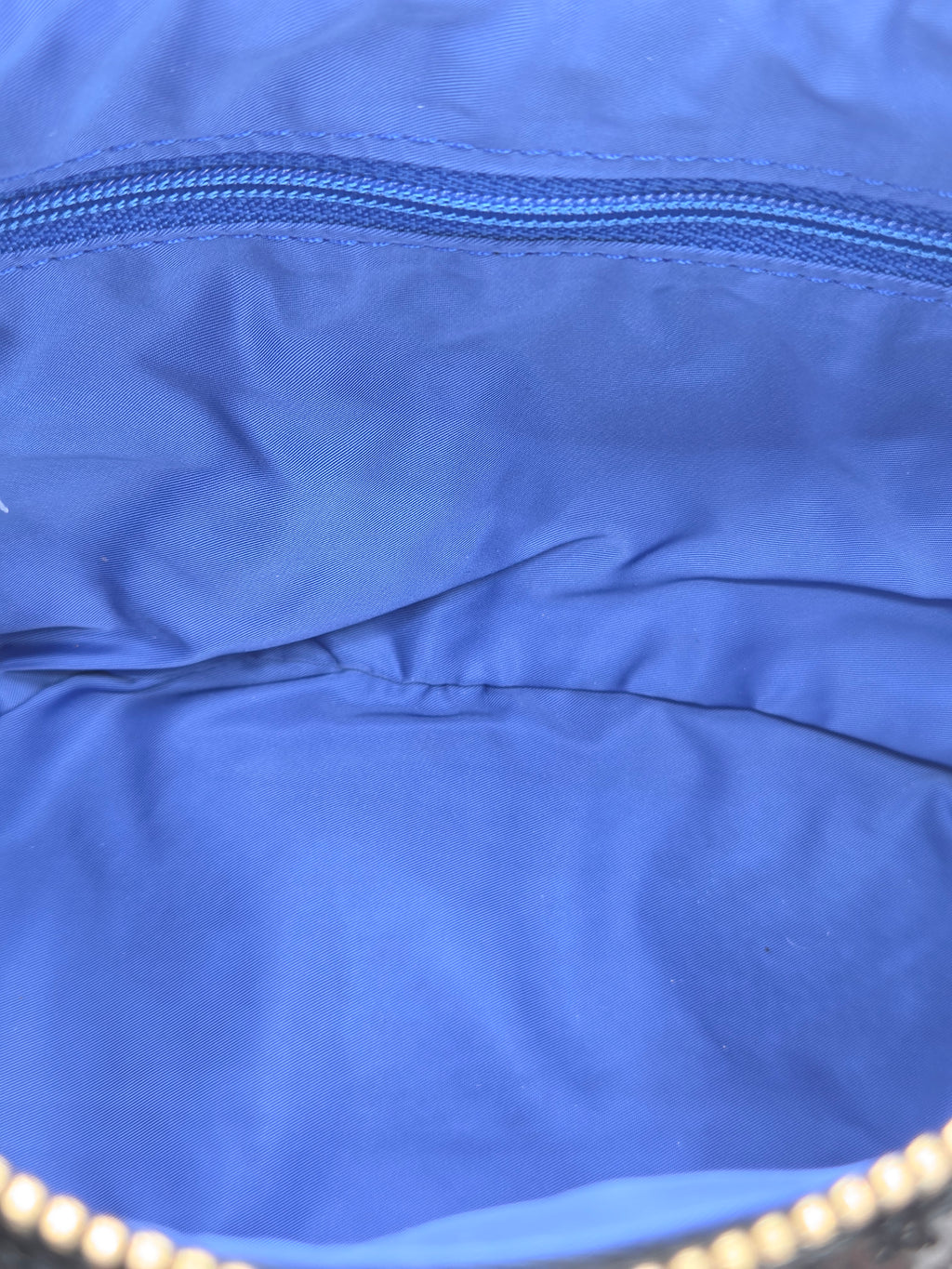 Close-up of the interior lining of a blue bag, showing a blue zipper and fabric texture.