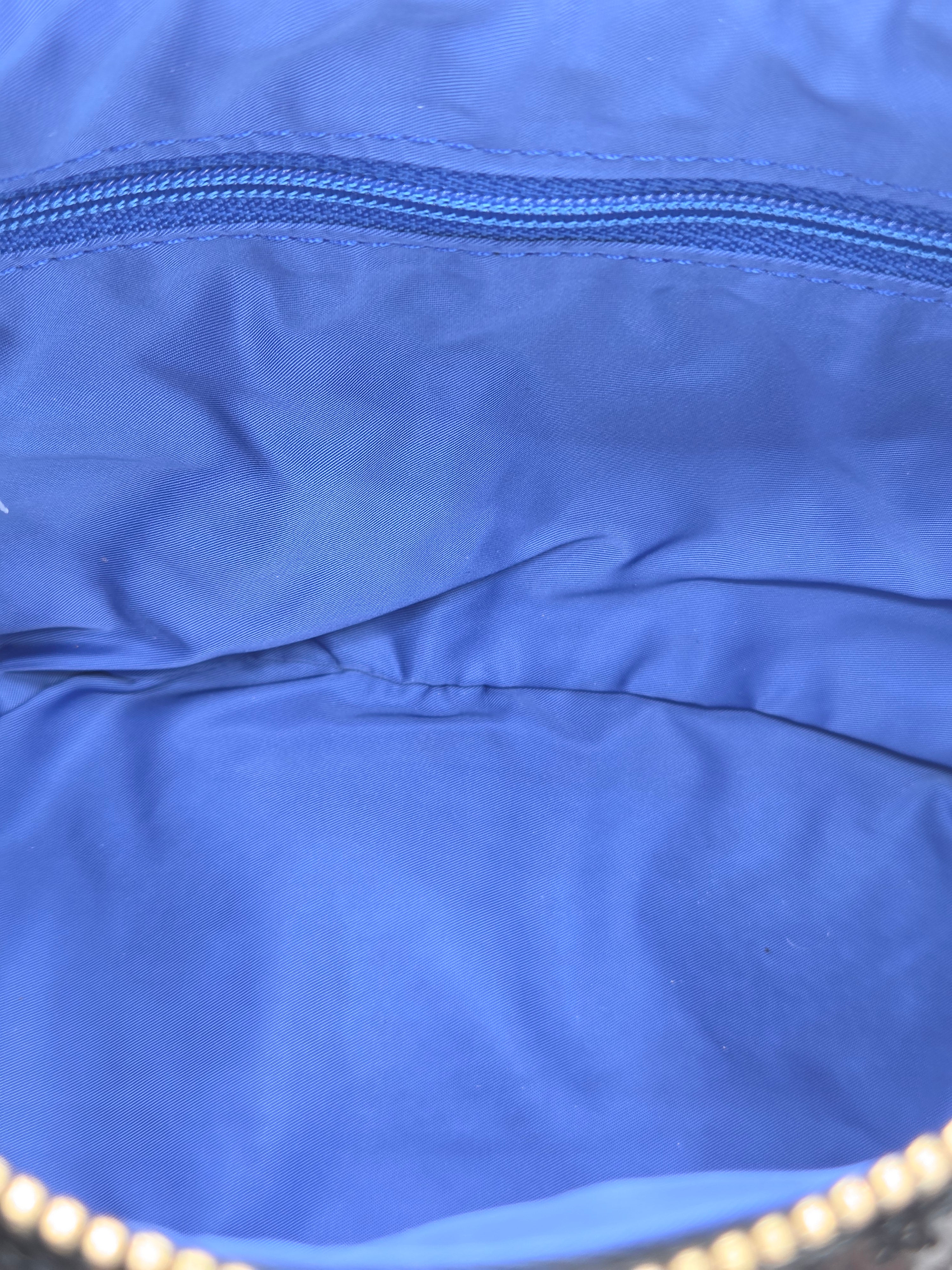 Close-up of the interior lining of a blue bag, showing a blue zipper and fabric texture.