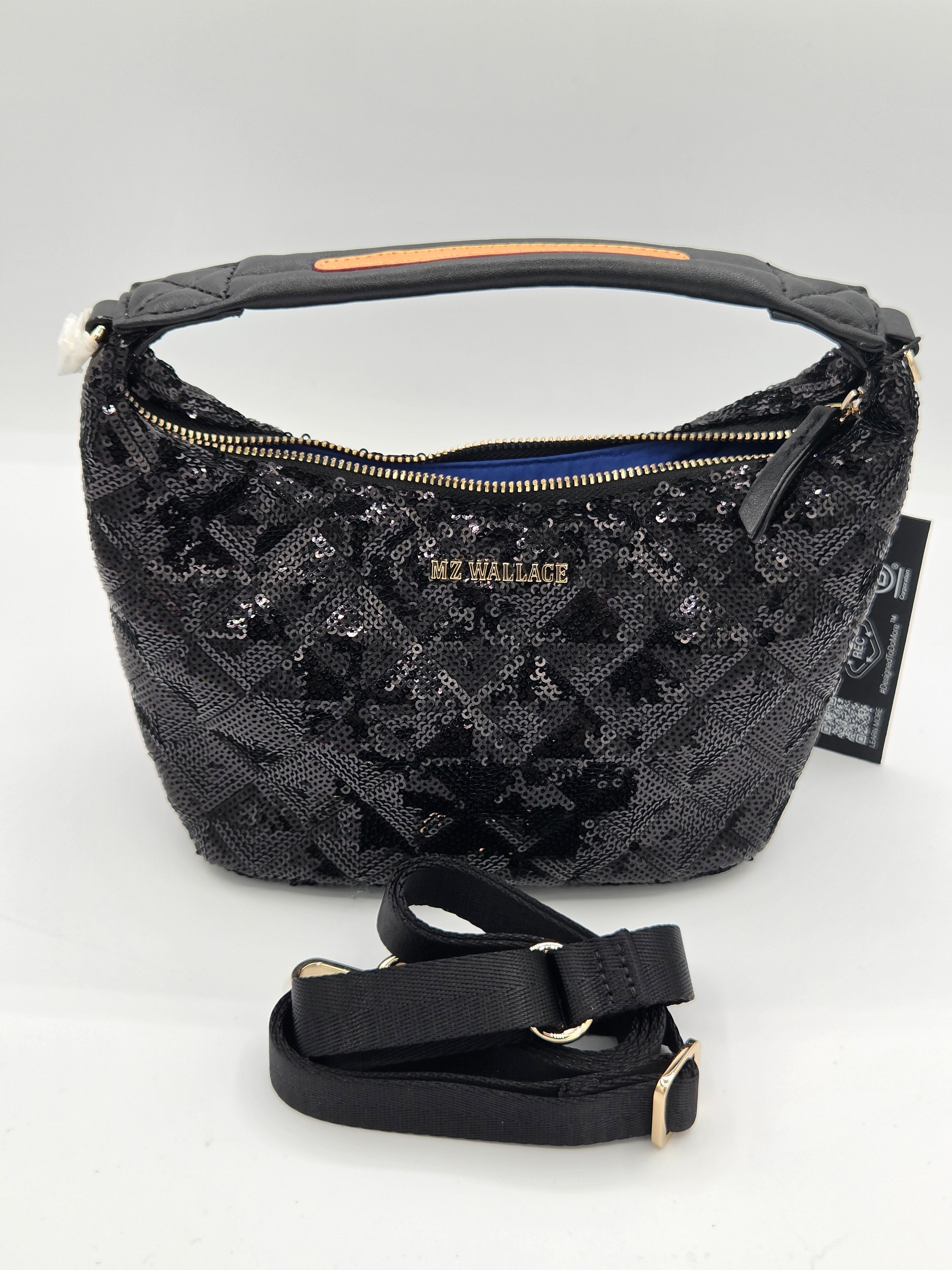 A black MK Wallace hobo shoulder bag covered in sequined monogram pattern, featuring a top handle, gold zipper, and a detachable black shoulder strap placed in front on a light gray background.