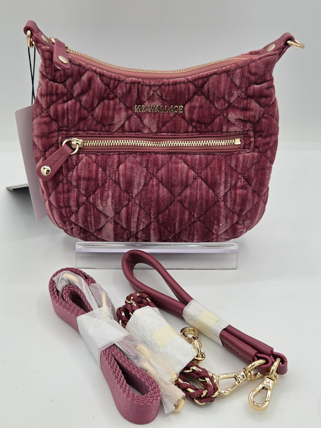 A burgundy quilted velvet shoulder bag with gold-tone hardware, displayed with its matching detachable woven strap on a white background.