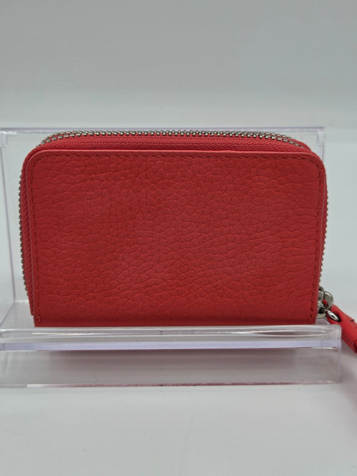 A red pebbled leather zip-around wallet with a silver-tone zipper, displayed on a clear acrylic stand against a light gray background.