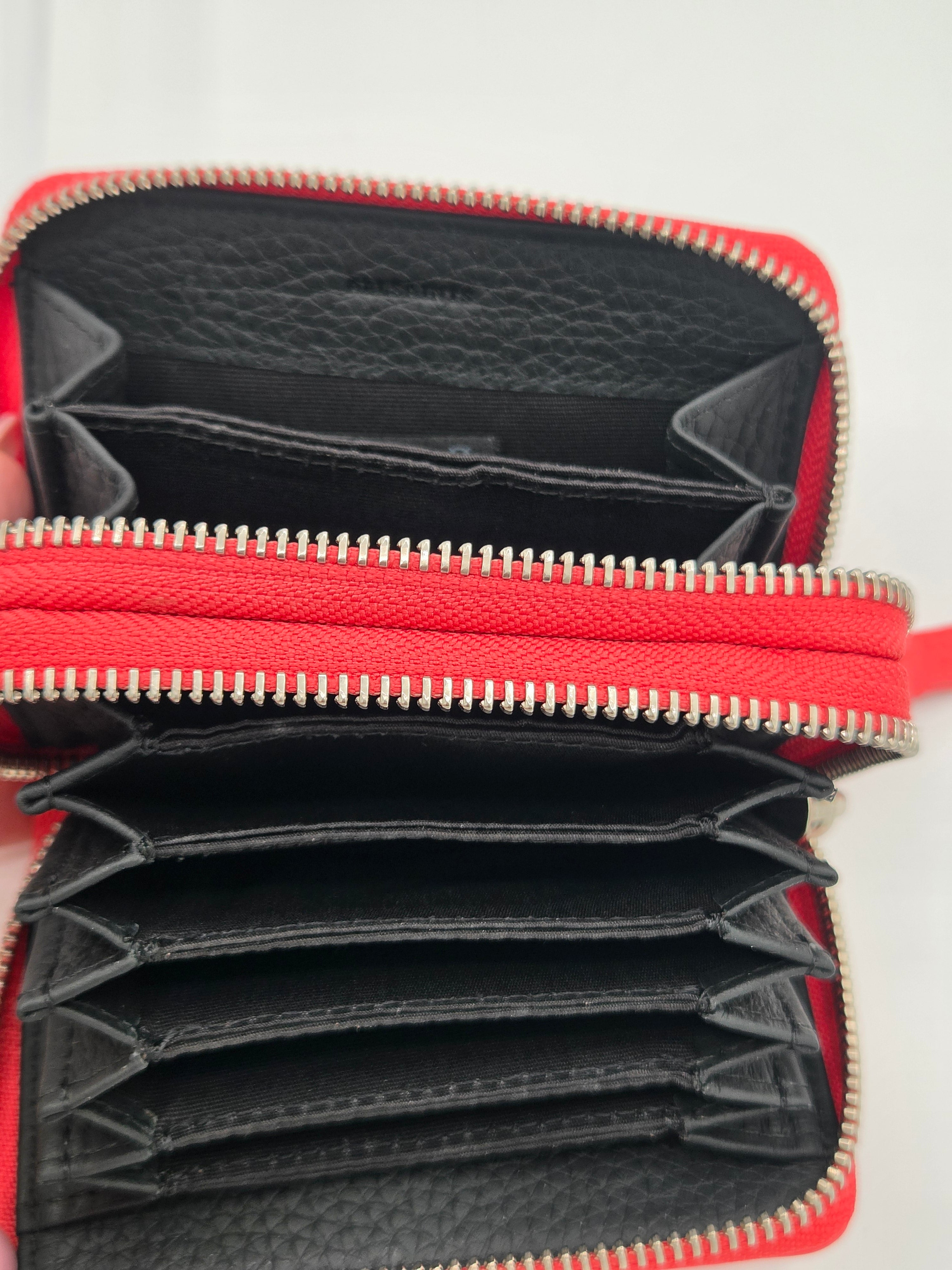 An open red and black zip-around wallet with multiple card slots and interior compartments, shown against a plain light background.