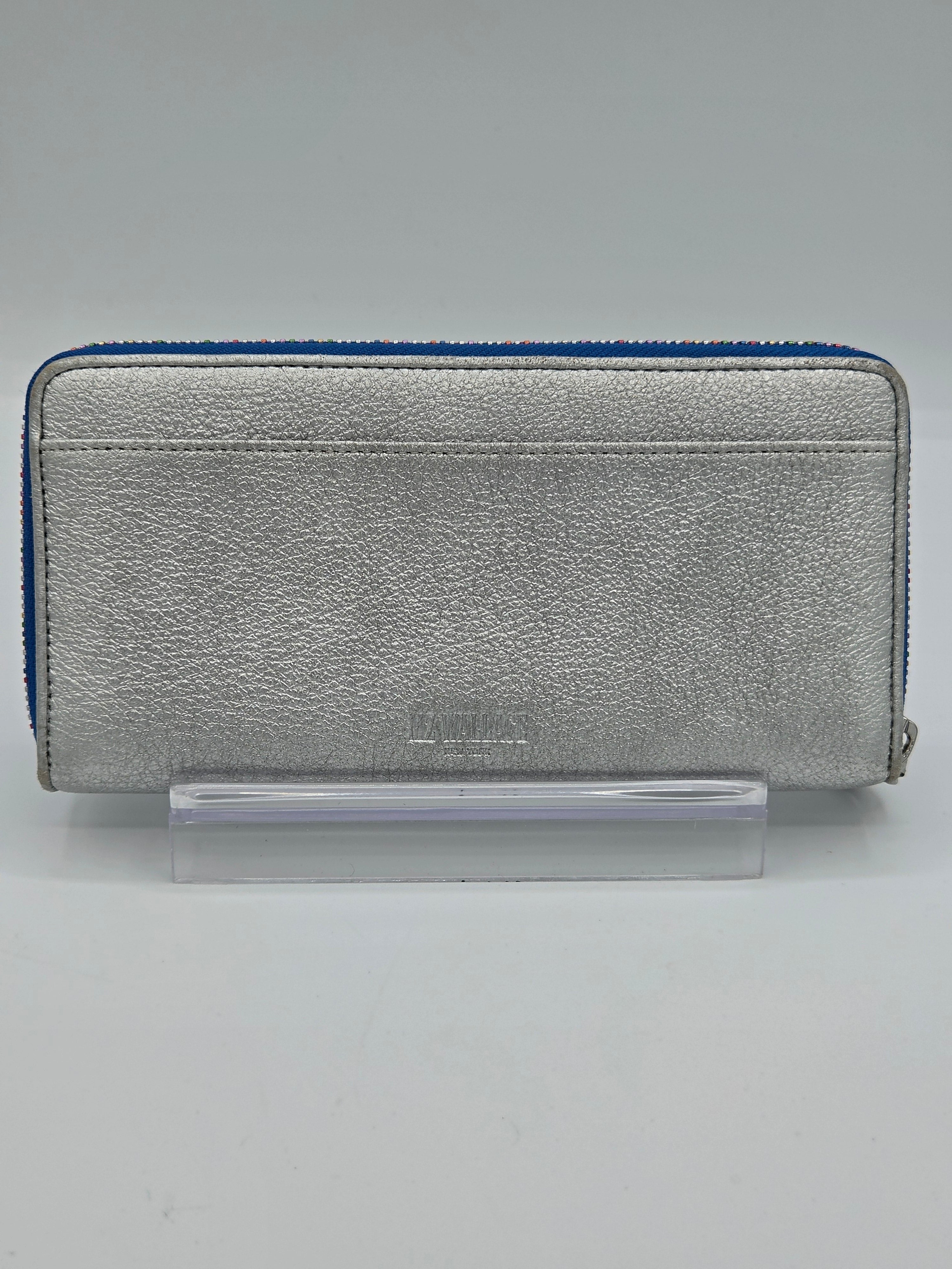 A silver textured leather zip-around wallet with a blue zipper trim, displayed on a clear acrylic stand against a neutral gray background.