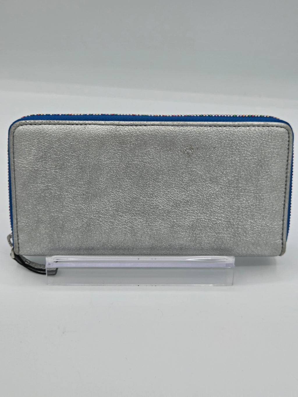 A silver textured leather zip-around wallet with a blue zipper trim, displayed on a clear acrylic stand against a light gray background.