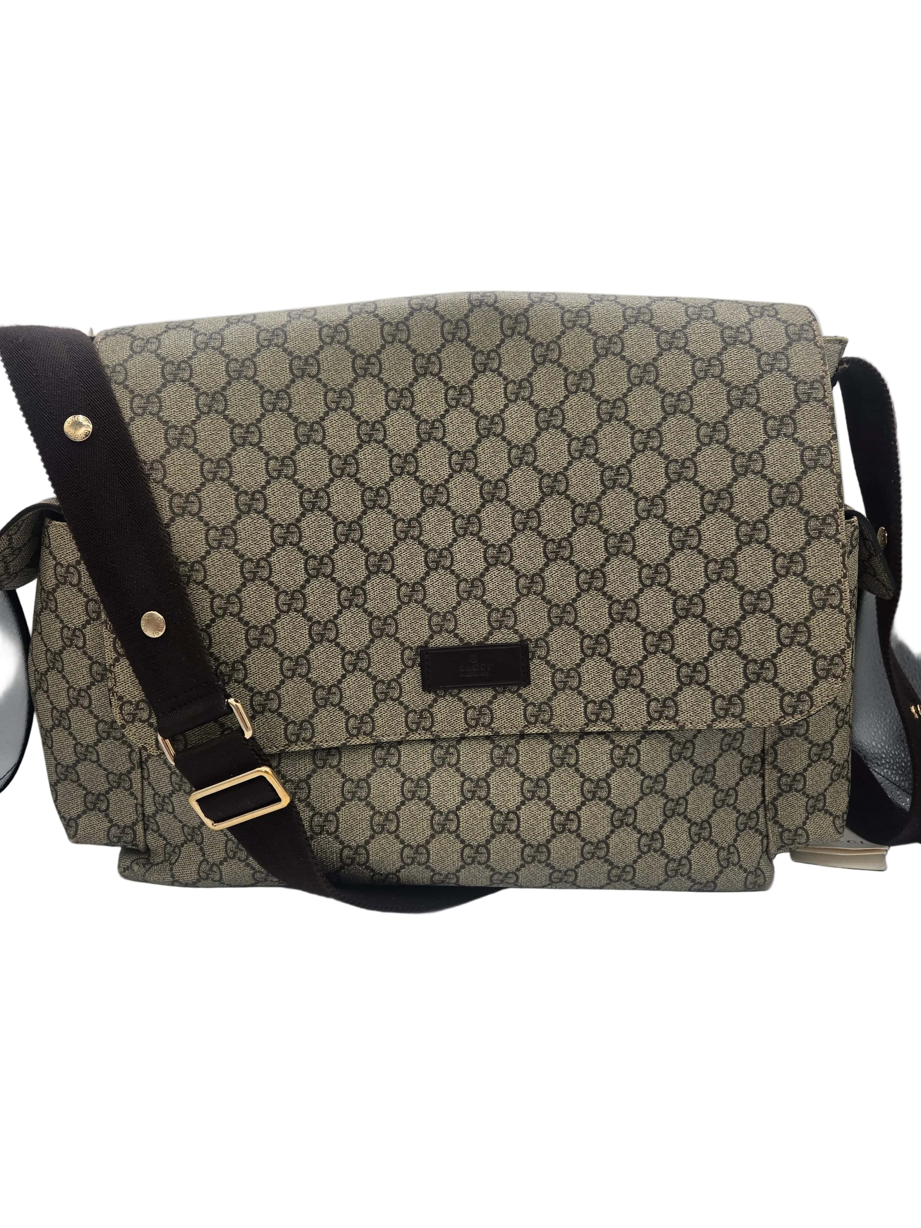 A vintage-style shoulder bag featuring the classic beige and brown GG monogram canvas, a dark brown leather strap with gold-tone hardware, and a small black leather brand plaque on the front flap.