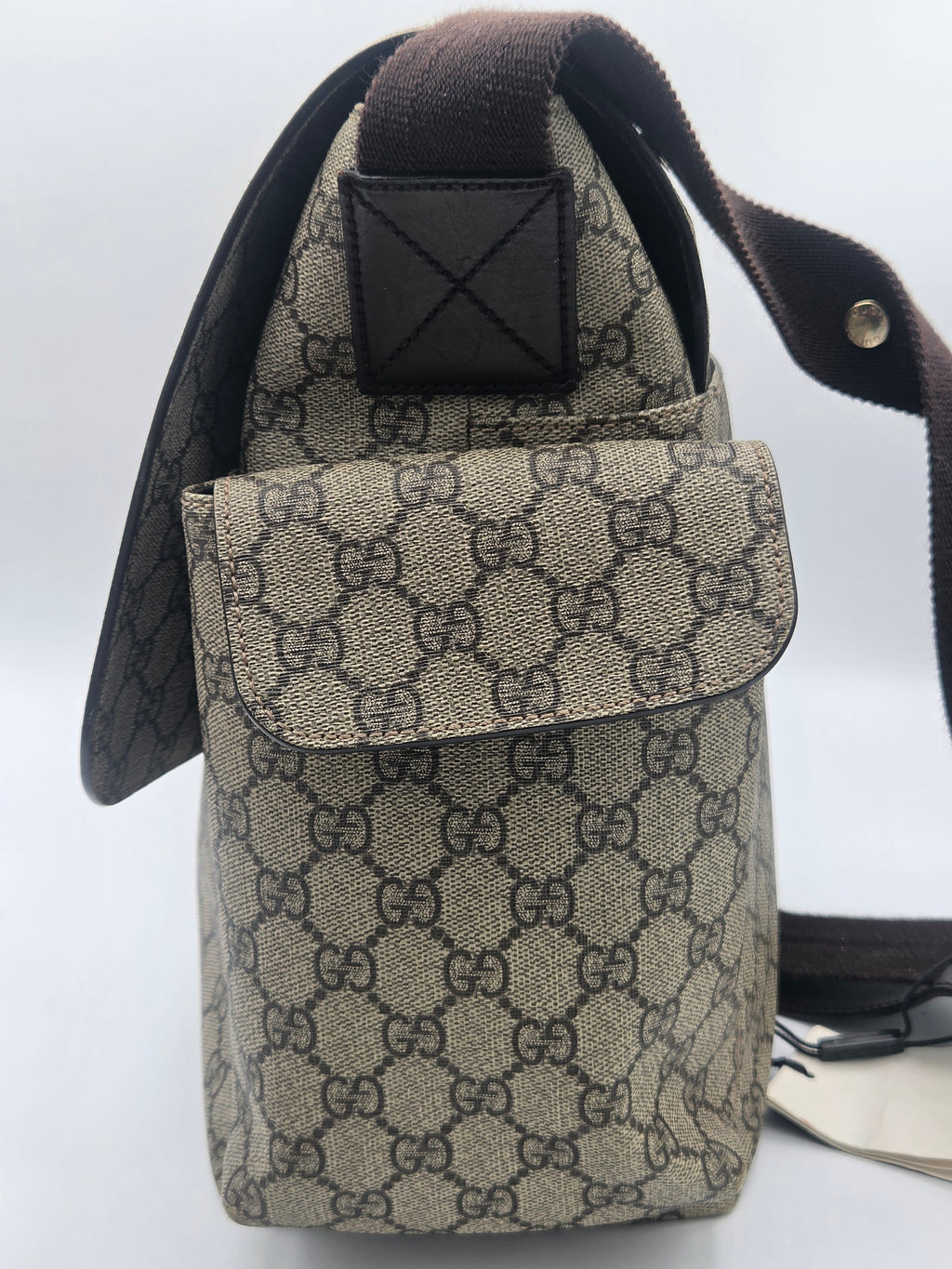 A Gucci shoulder bag in beige GG Supreme canvas with dark brown trim and strap, shown against a plain light background.