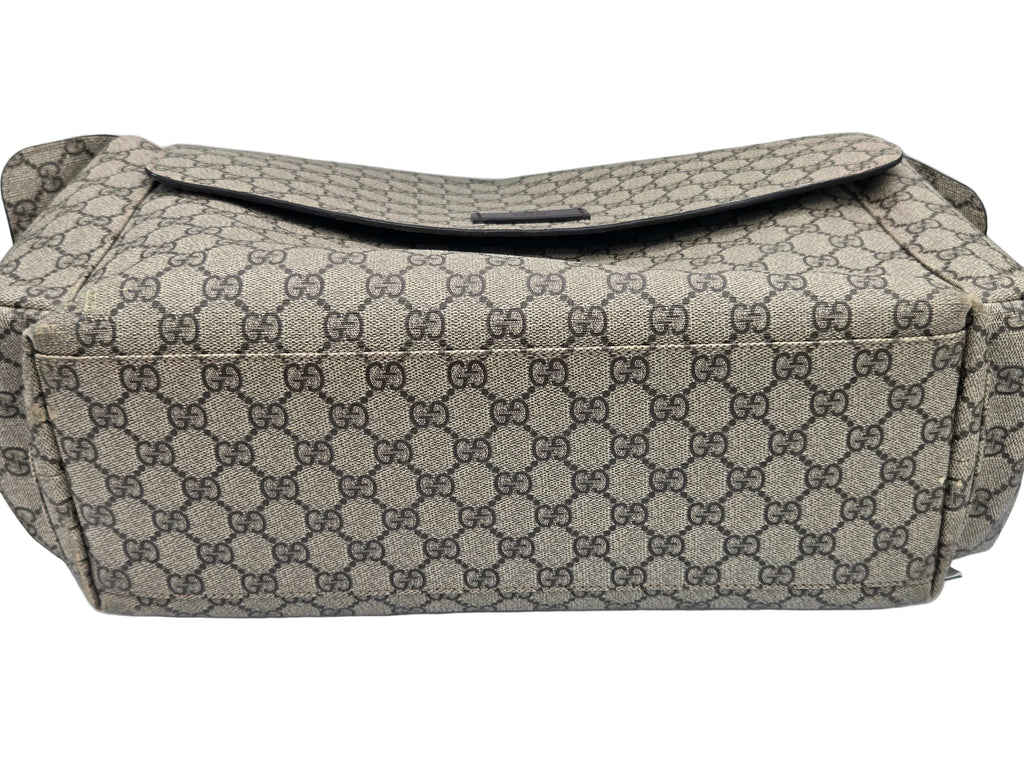 A Gucci shoulder bag in the signature GG Supreme canvas, featuring a beige and brown monogram pattern with a dark brown leather strap and trim, photographed on a white background.