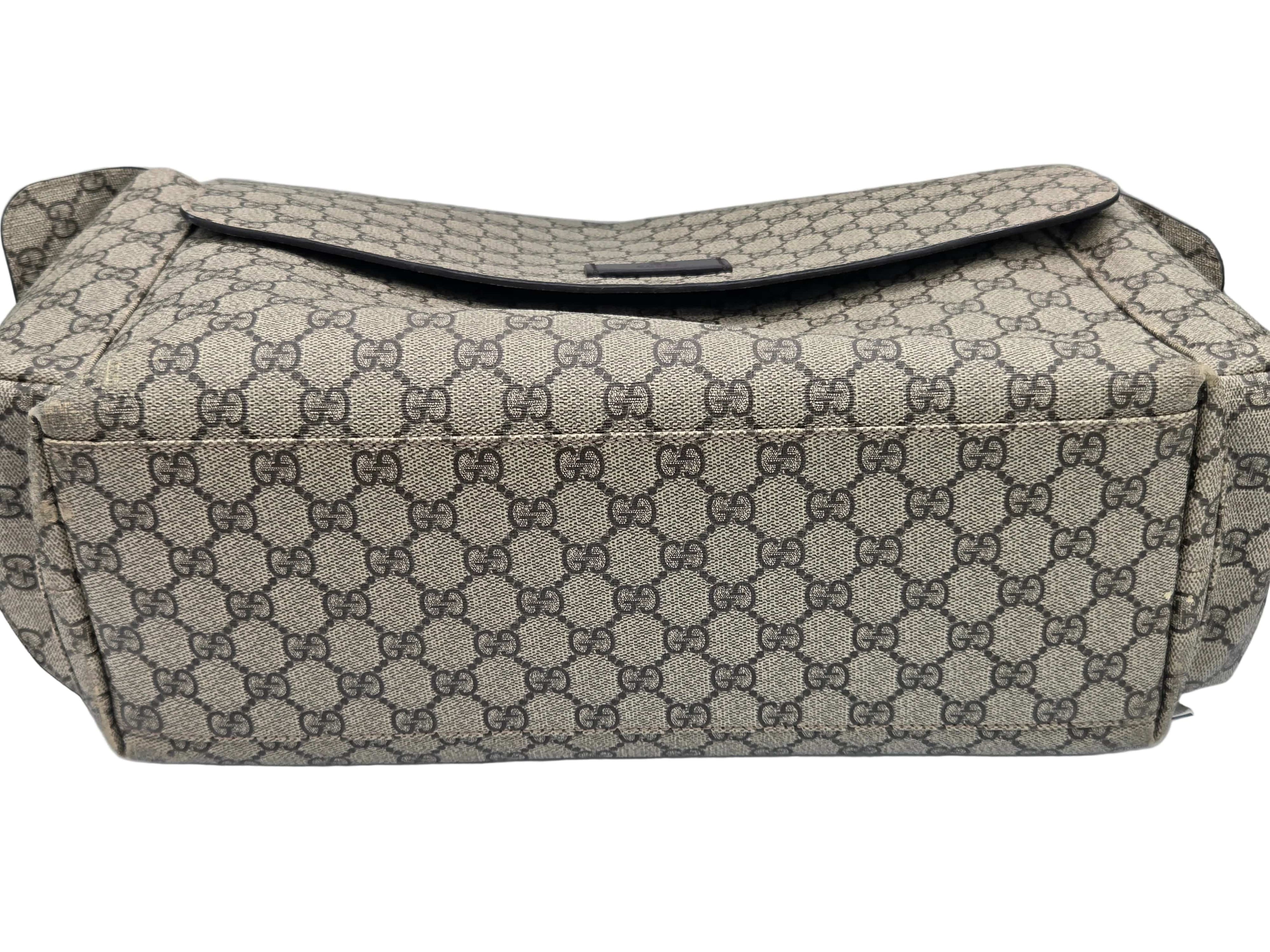 A Gucci shoulder bag in the signature GG Supreme canvas, featuring a beige and brown monogram pattern with a dark brown leather strap and trim, photographed on a white background.