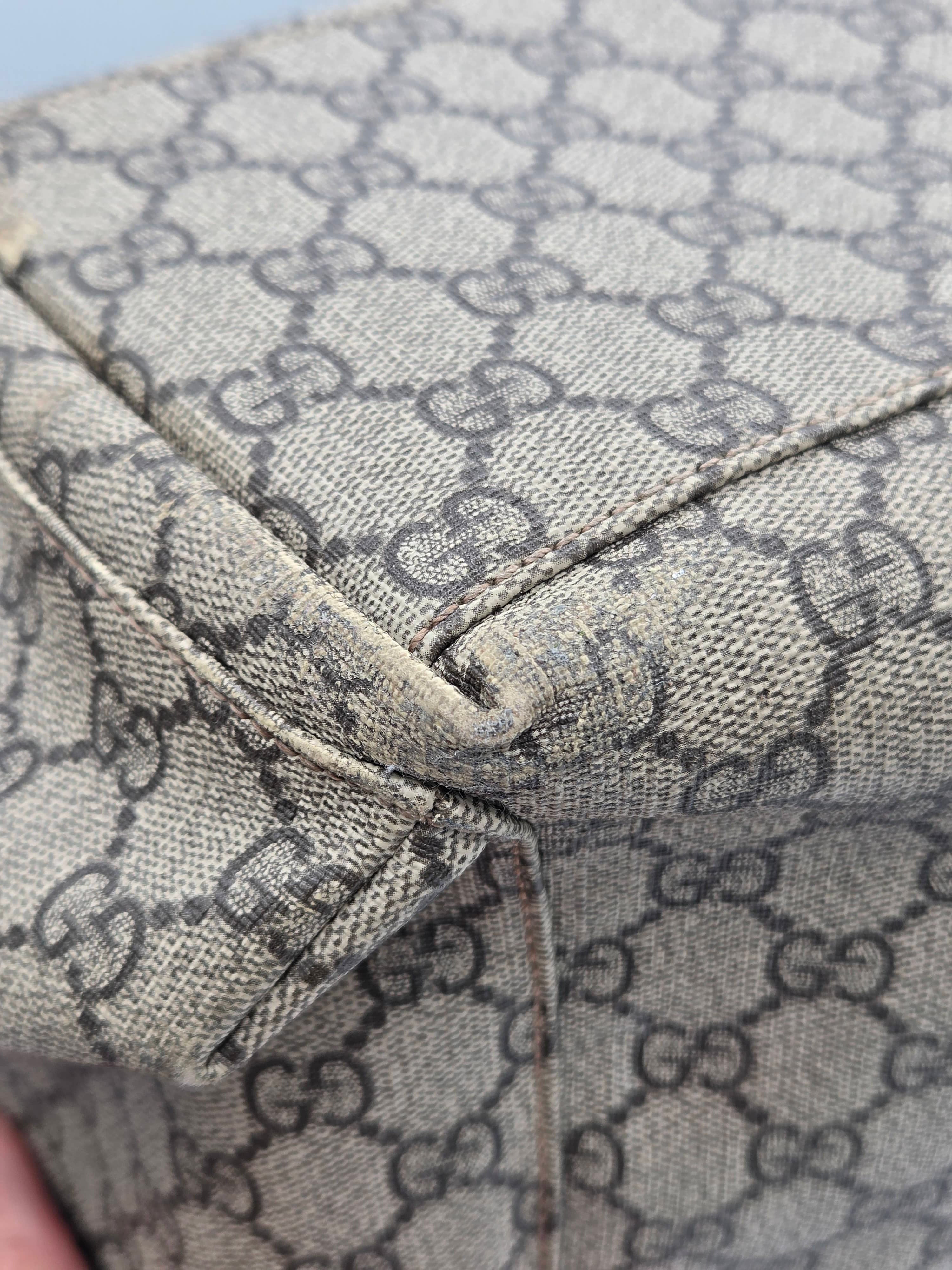 Close-up of a beige and brown monogram canvas material with a visible fold and stitching detail.