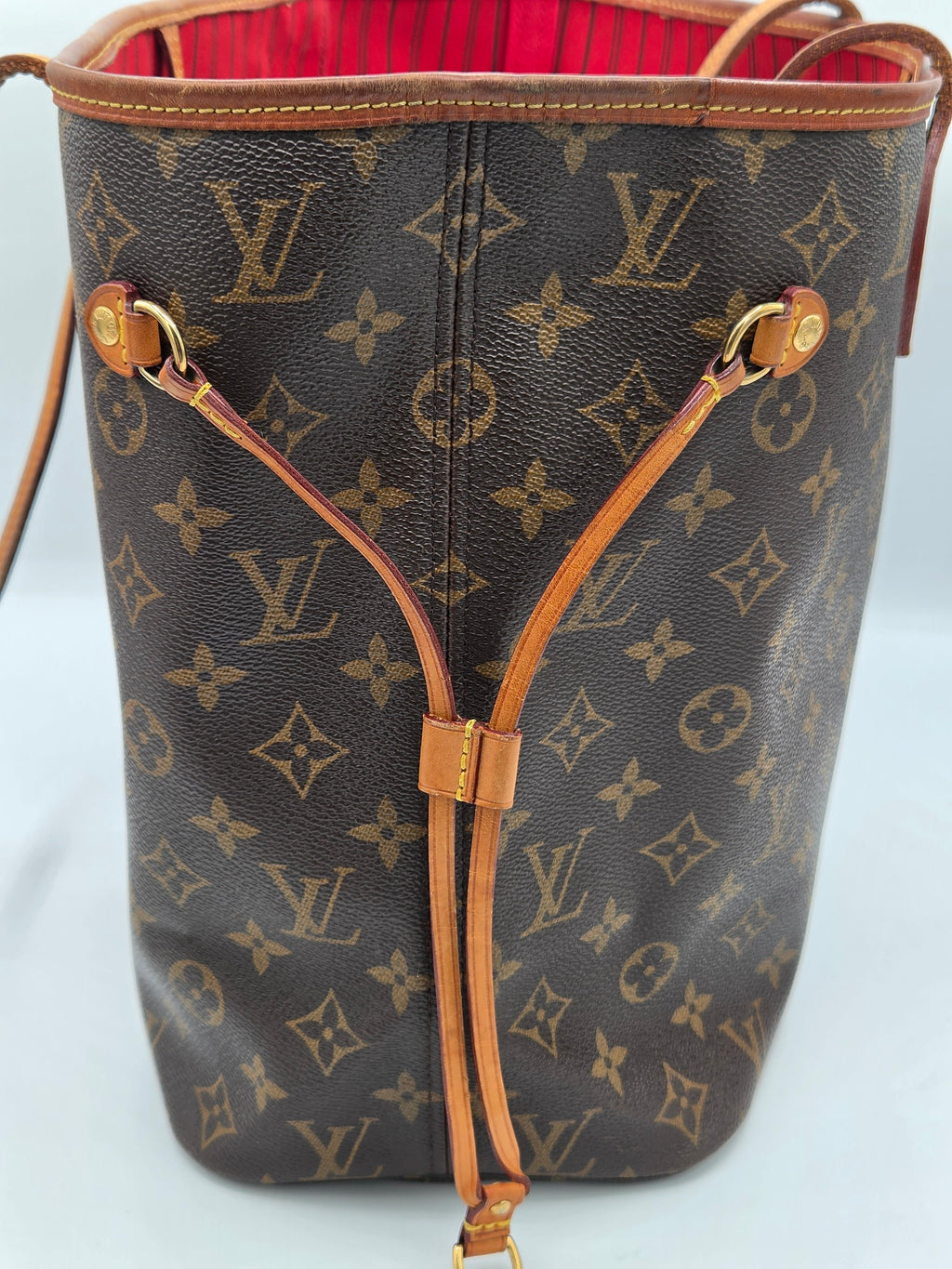 A Louis Vuitton Neverfull tote bag in brown monogram canvas with tan leather trim and drawstring straps, shown against a plain light background.