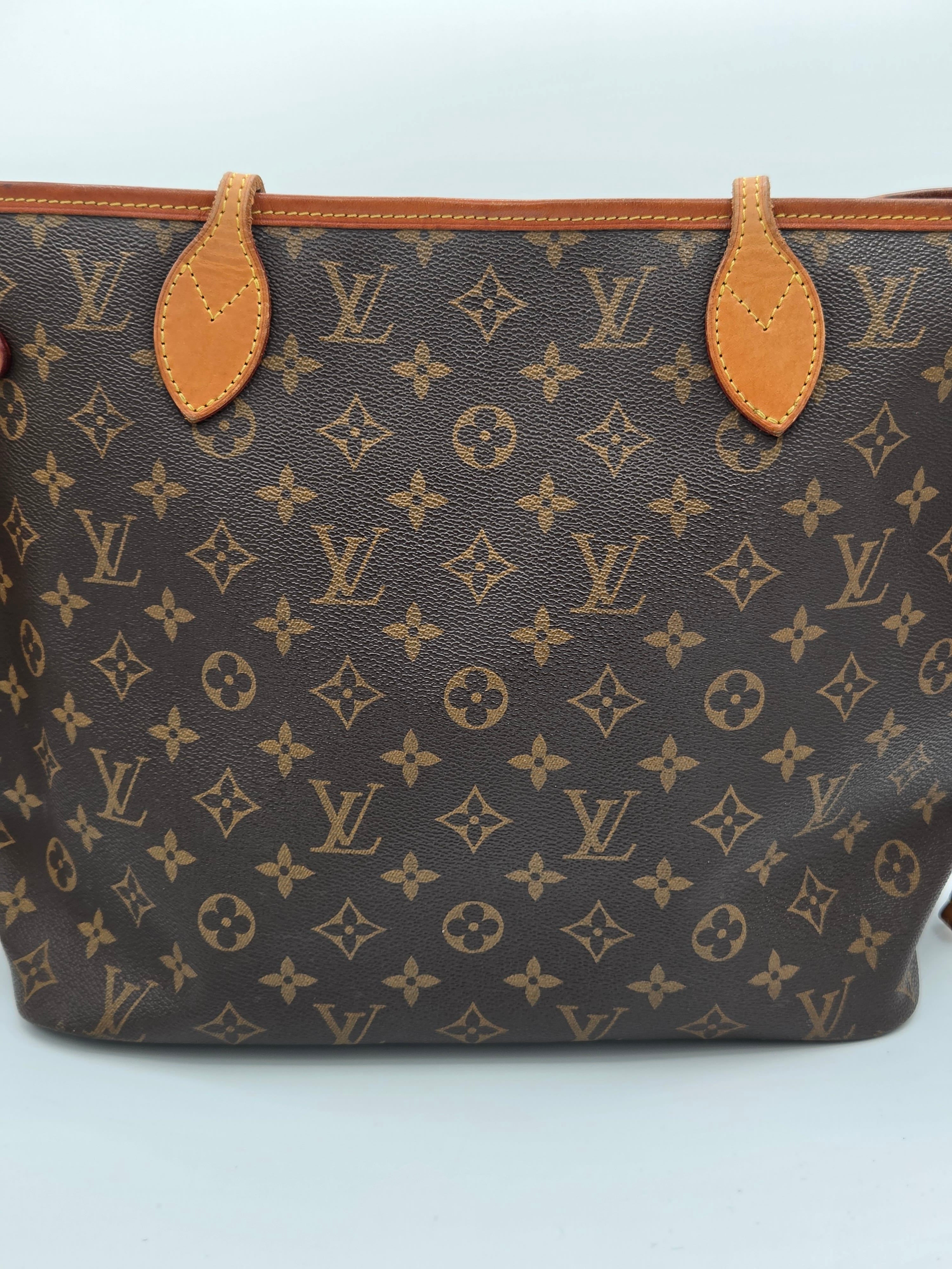 Louis Vuitton monogram canvas tote bag in dark brown with tan leather trim and handle attachments, photographed against a light gray background.