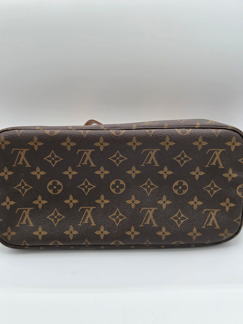 A Louis Vuitton monogram canvas toiletry bag in brown and tan, photographed against a plain light gray background.