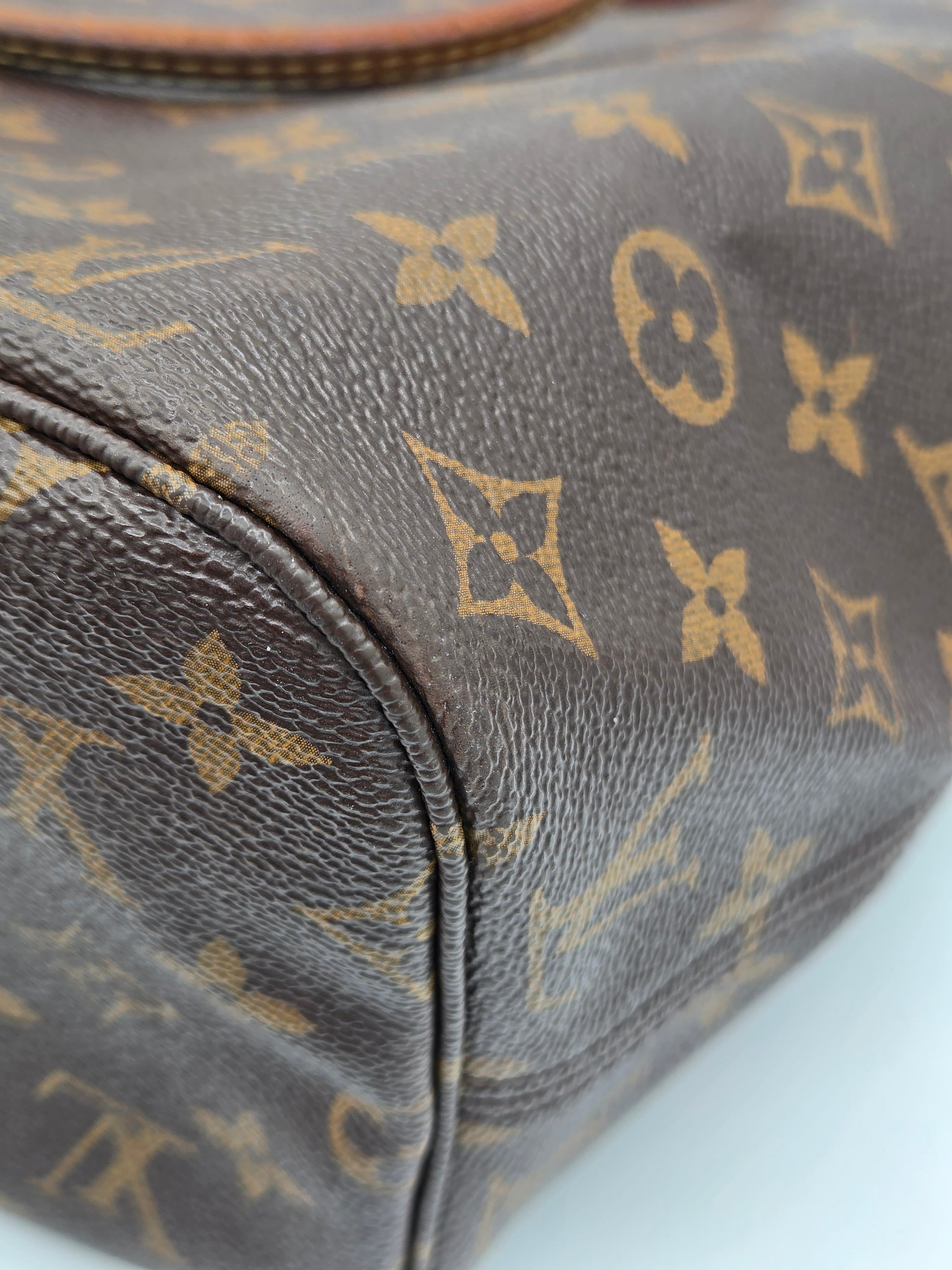 Close-up of a brown coated canvas bag with the classic tan/gold Louis Vuitton monogram pattern, showing the textured leather grain and a curved seam.