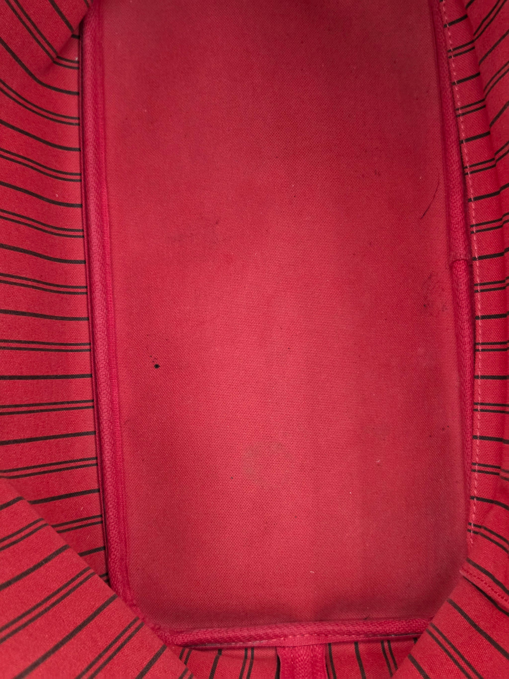 Close-up of a red fabric interior with a smooth central panel and striped red-and-black fabric lining around the edges.