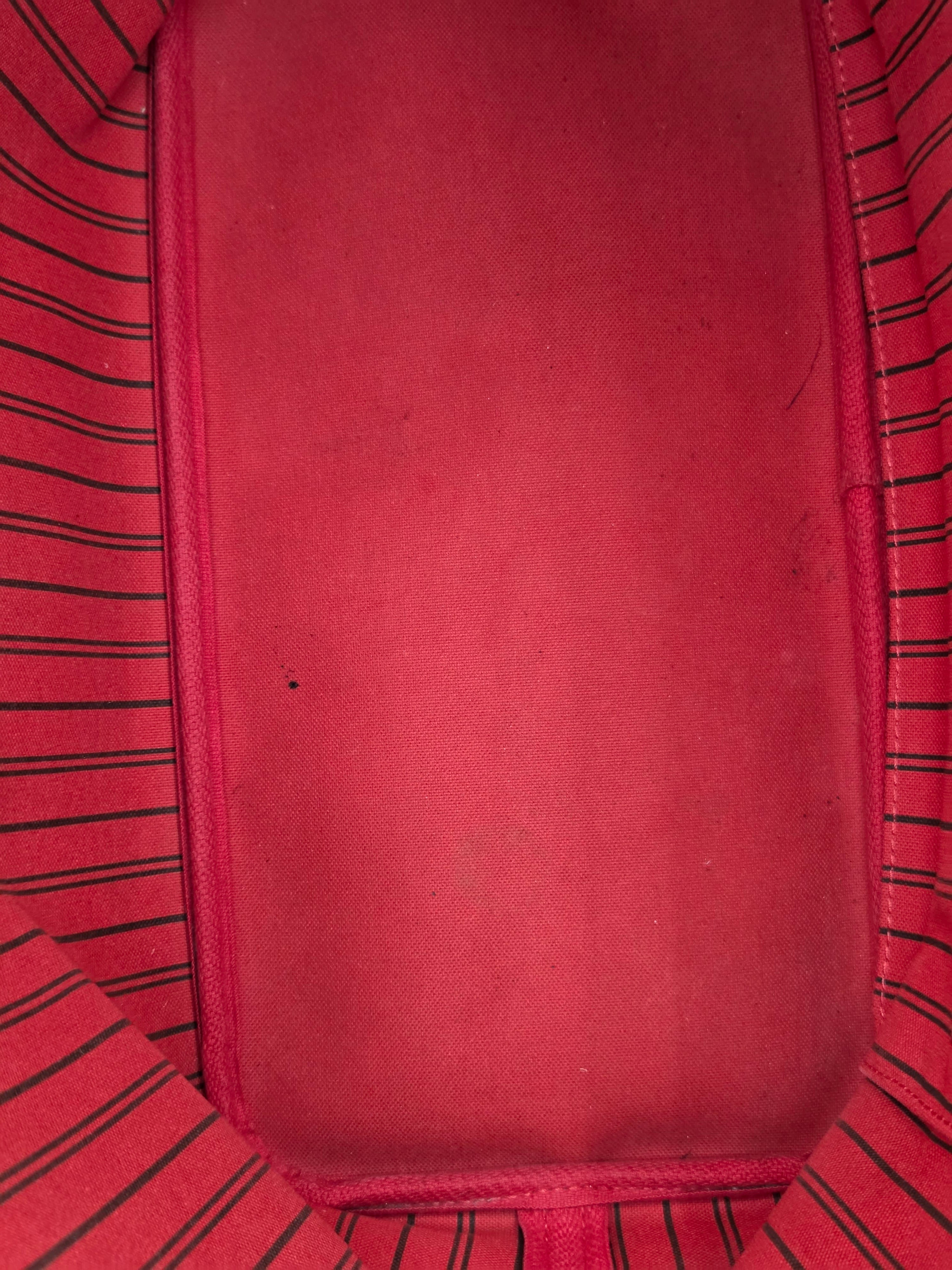 Close-up of a red fabric interior with a smooth central panel and striped red-and-black fabric lining around the edges.